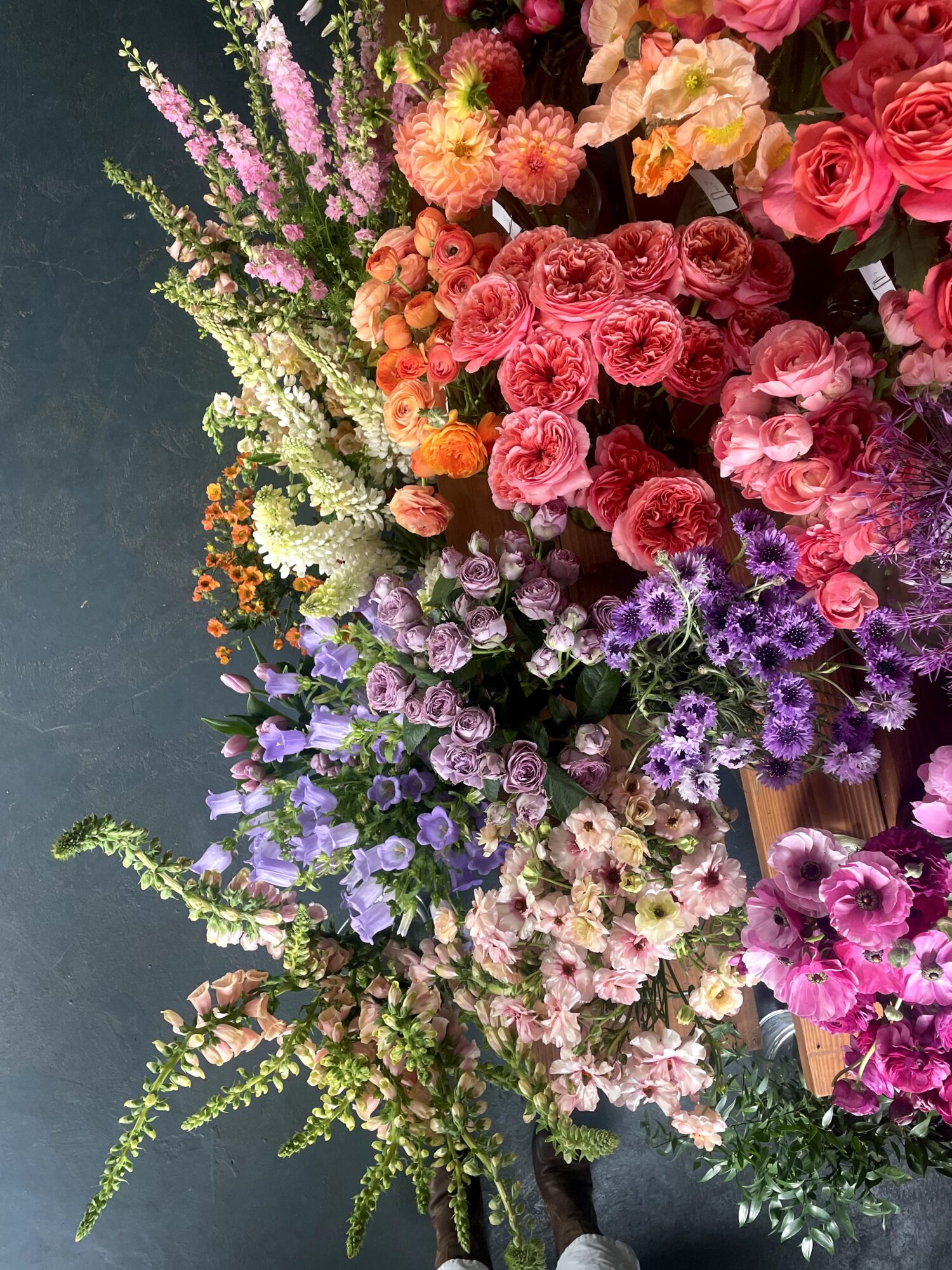 Colorful bouquet of various flowers including pink, purple, orange, and white blooms arranged against a dark background.
