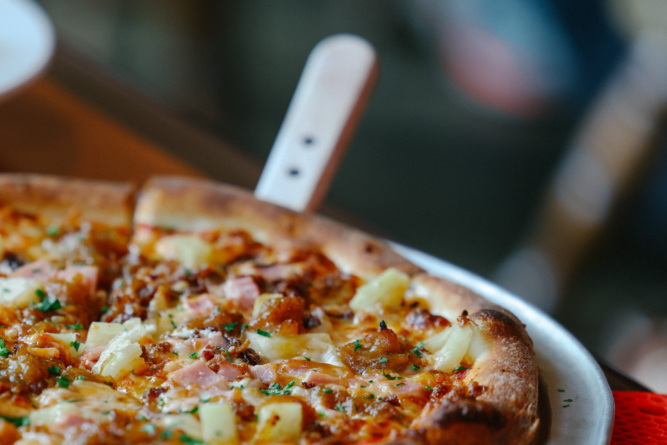 Pizza with toppings on a white plate, with a blurred background.