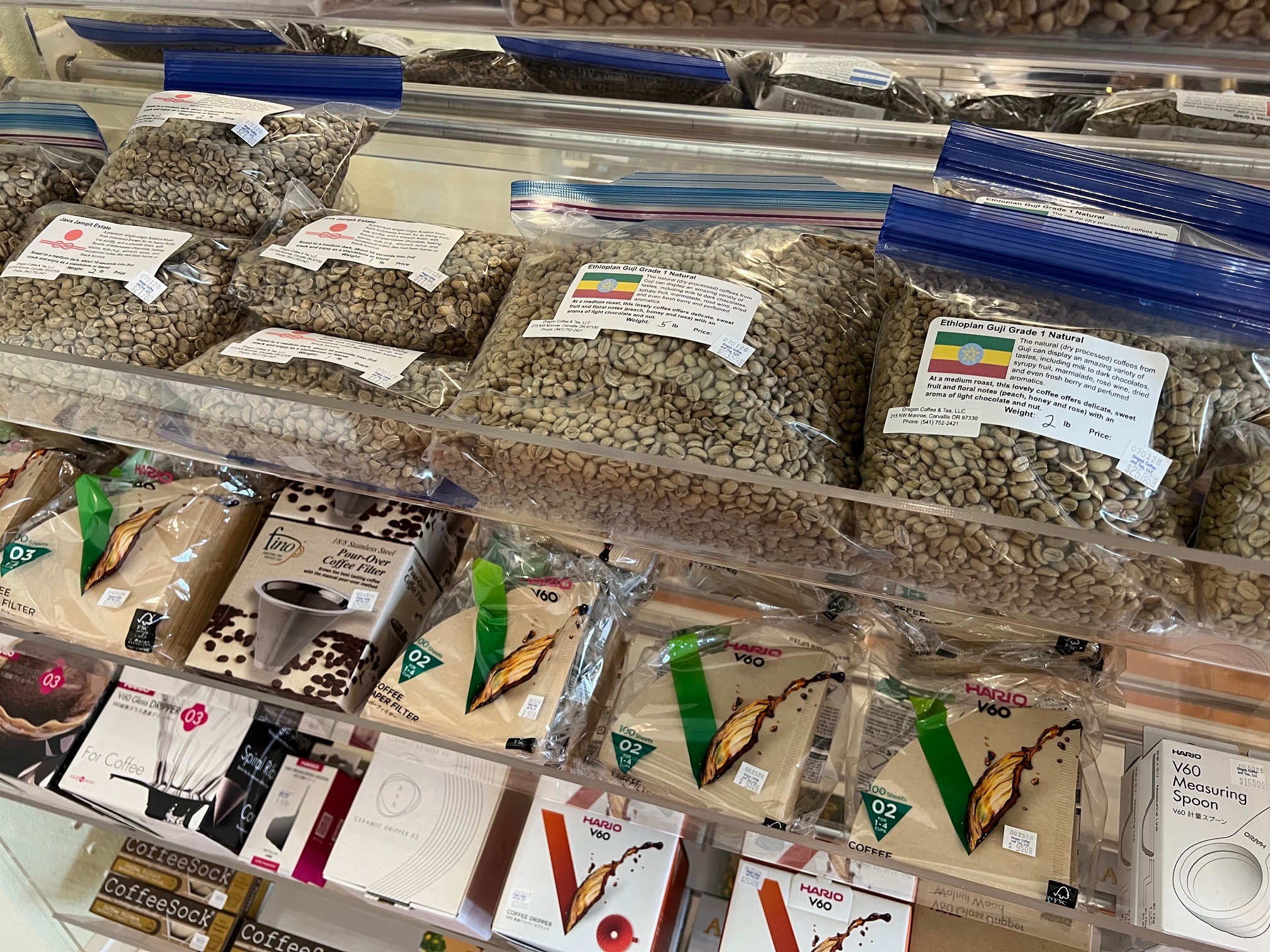 Bags of dried herbs or tea leaves on a store shelf, with some packaged products below, in a retail setting.