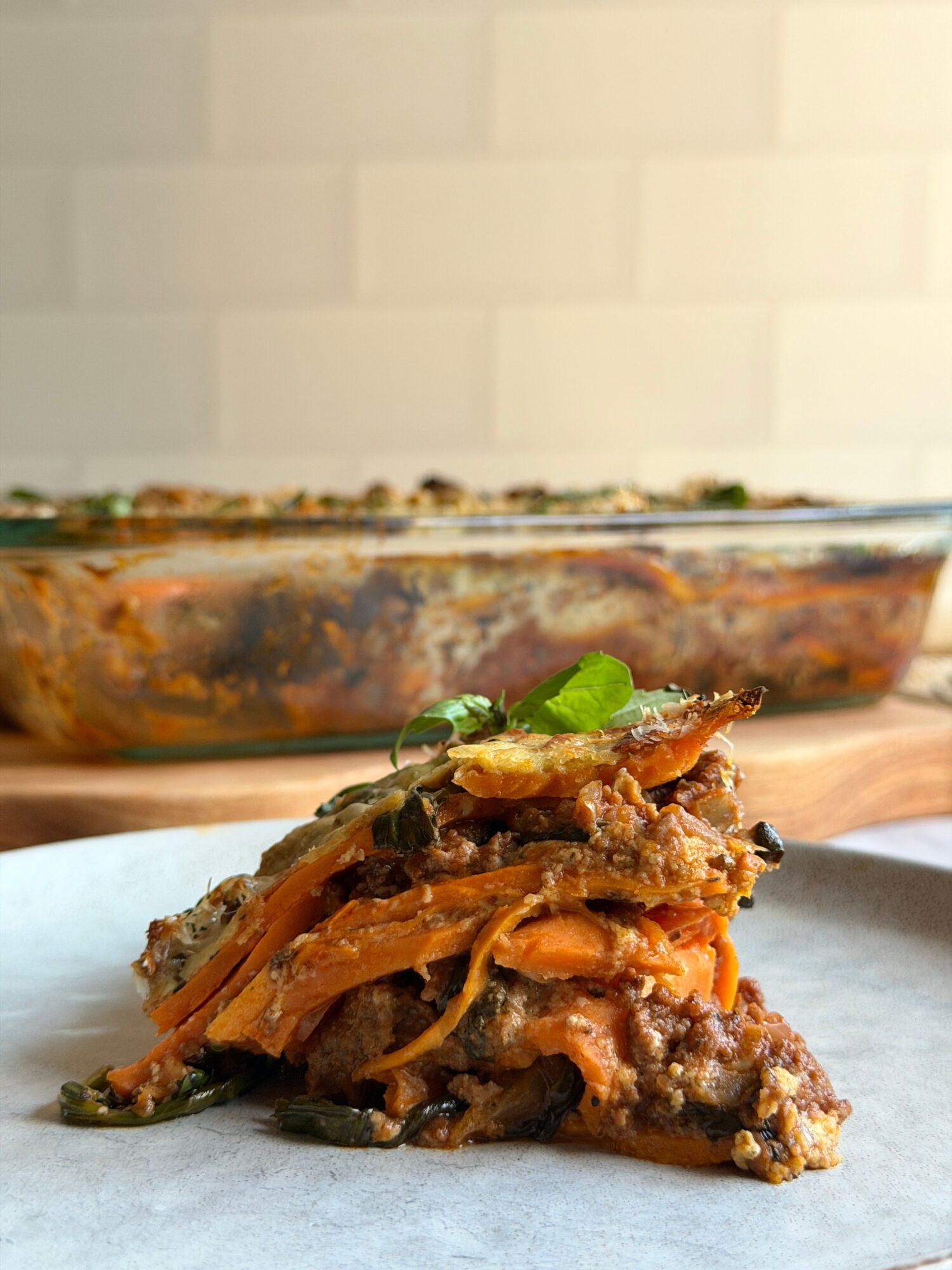 Close-up of a slice of meatloaf with vegetables on parchment paper, with a blurred loaf in the background.