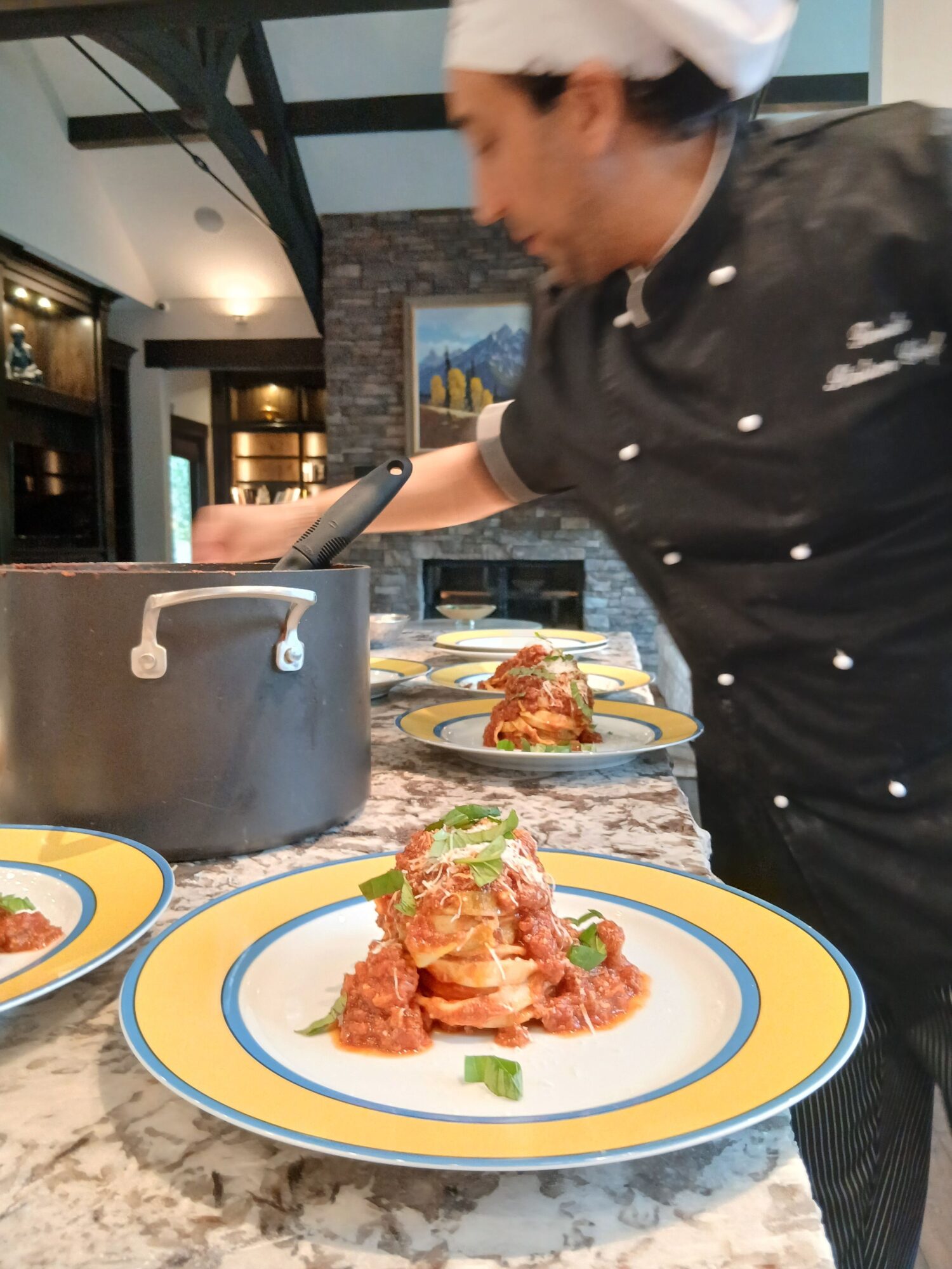 Person serving food at a table with plates of fried chicken, garnished with herbs, on colorful plates.