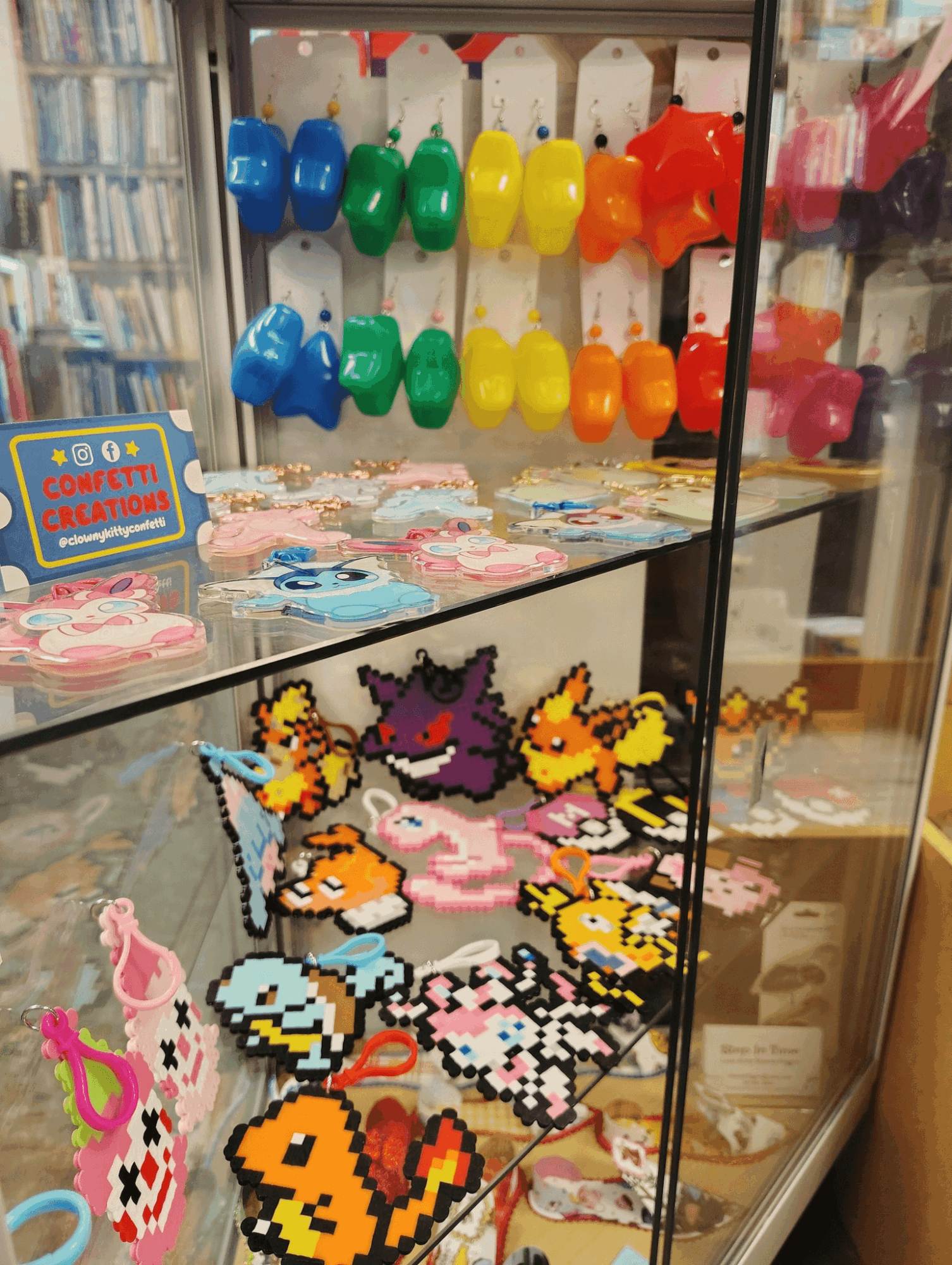 Display case with colorful pixel art Pokémon and accessories, shelves with toys, and a sign in the background.