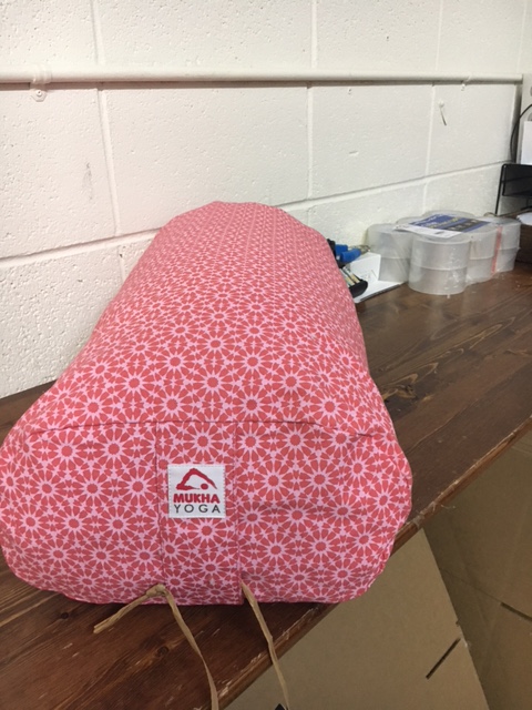 Pink heart-shaped object with a floral pattern and a label, placed on a wooden surface.