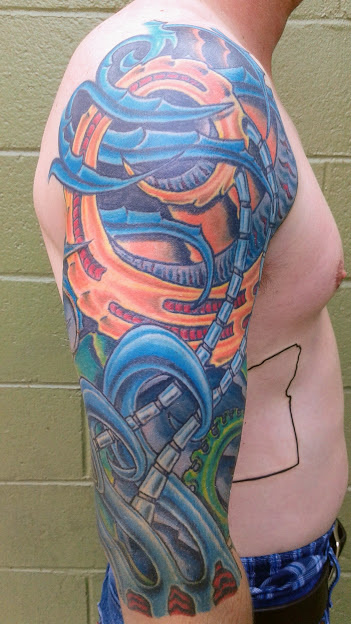 Colorful tattoo of a snake and mechanical elements on person's upper arm and shoulder, with a green background.