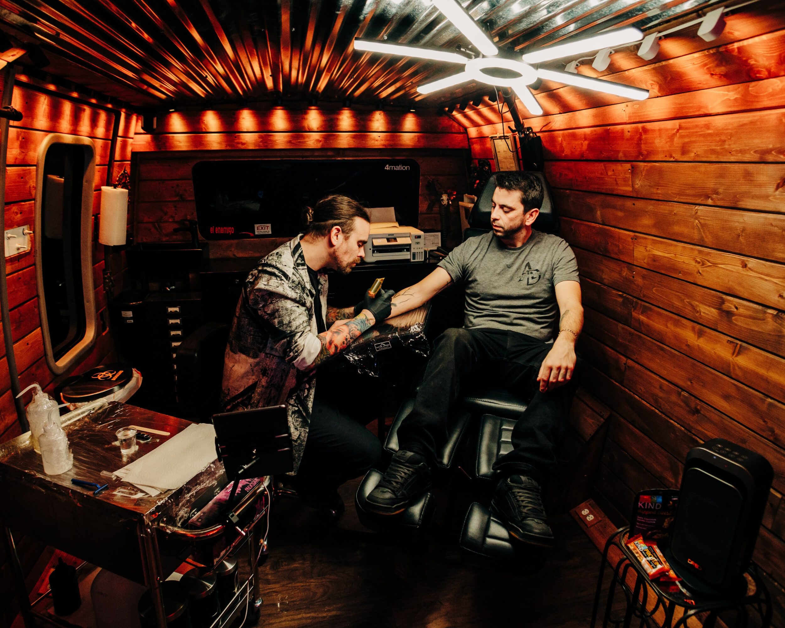 Two men shake hands in a cozy, wood-paneled room with warm lighting and musical equipment.
