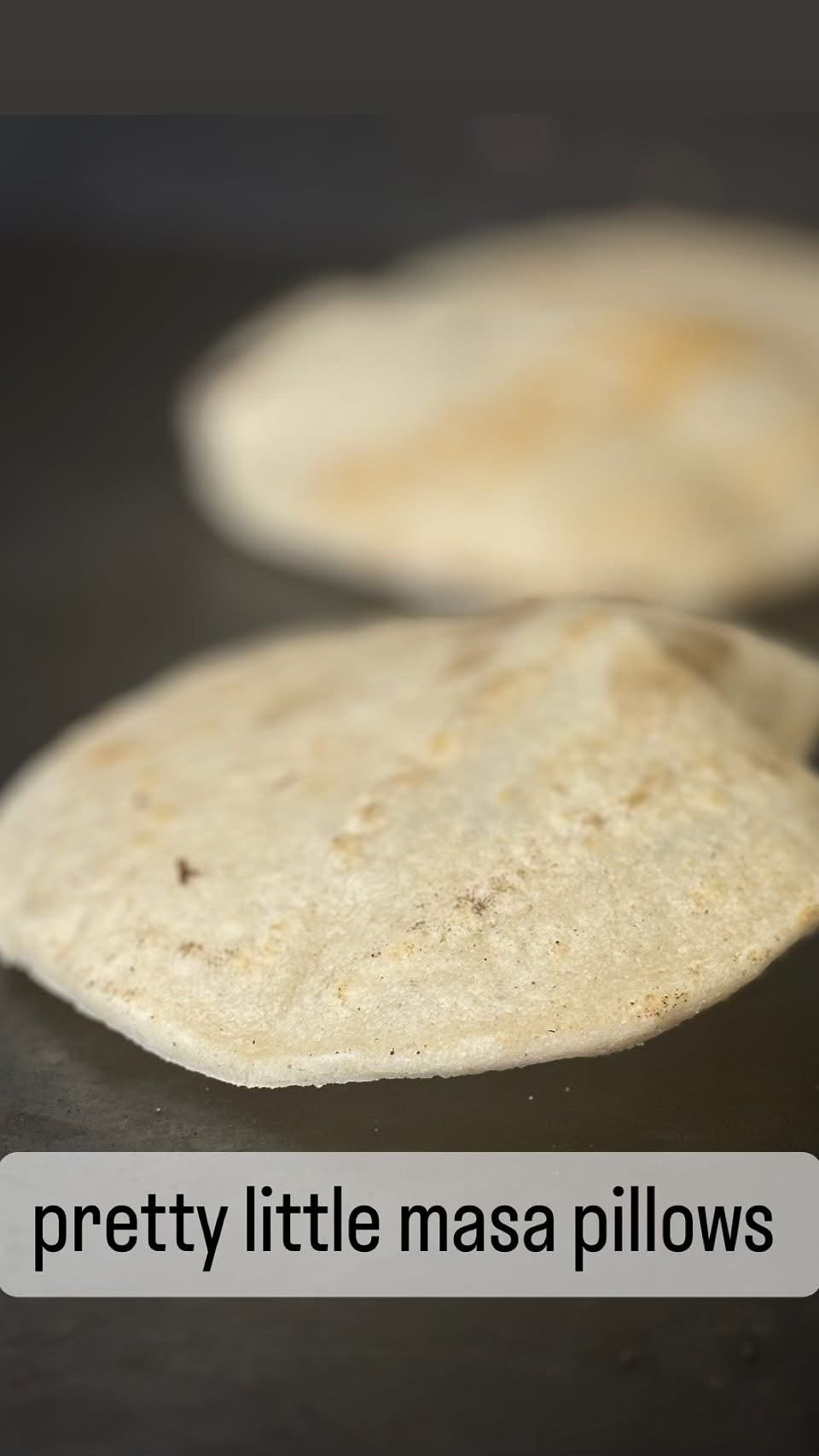 Two bread rolls on a dark surface, one in foreground and one blurred in background.