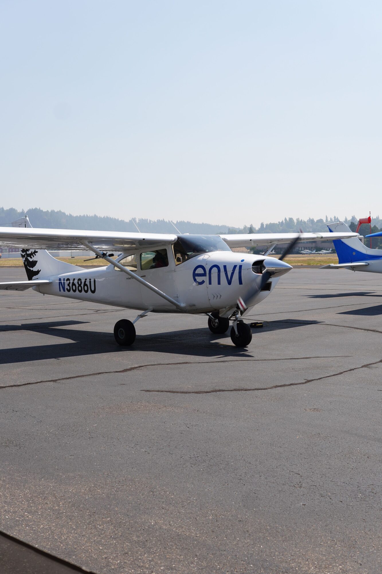 Small aircraft parked on tarmac with a clear sky and distant horizon in the background.
