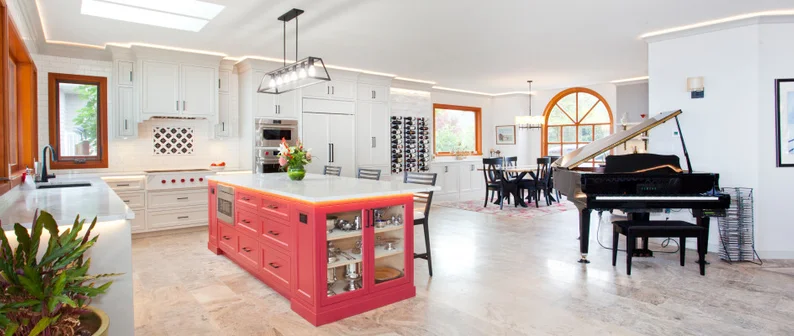 Bright kitchen and dining area with a pink island, black piano, and large windows, spacious and well-lit.