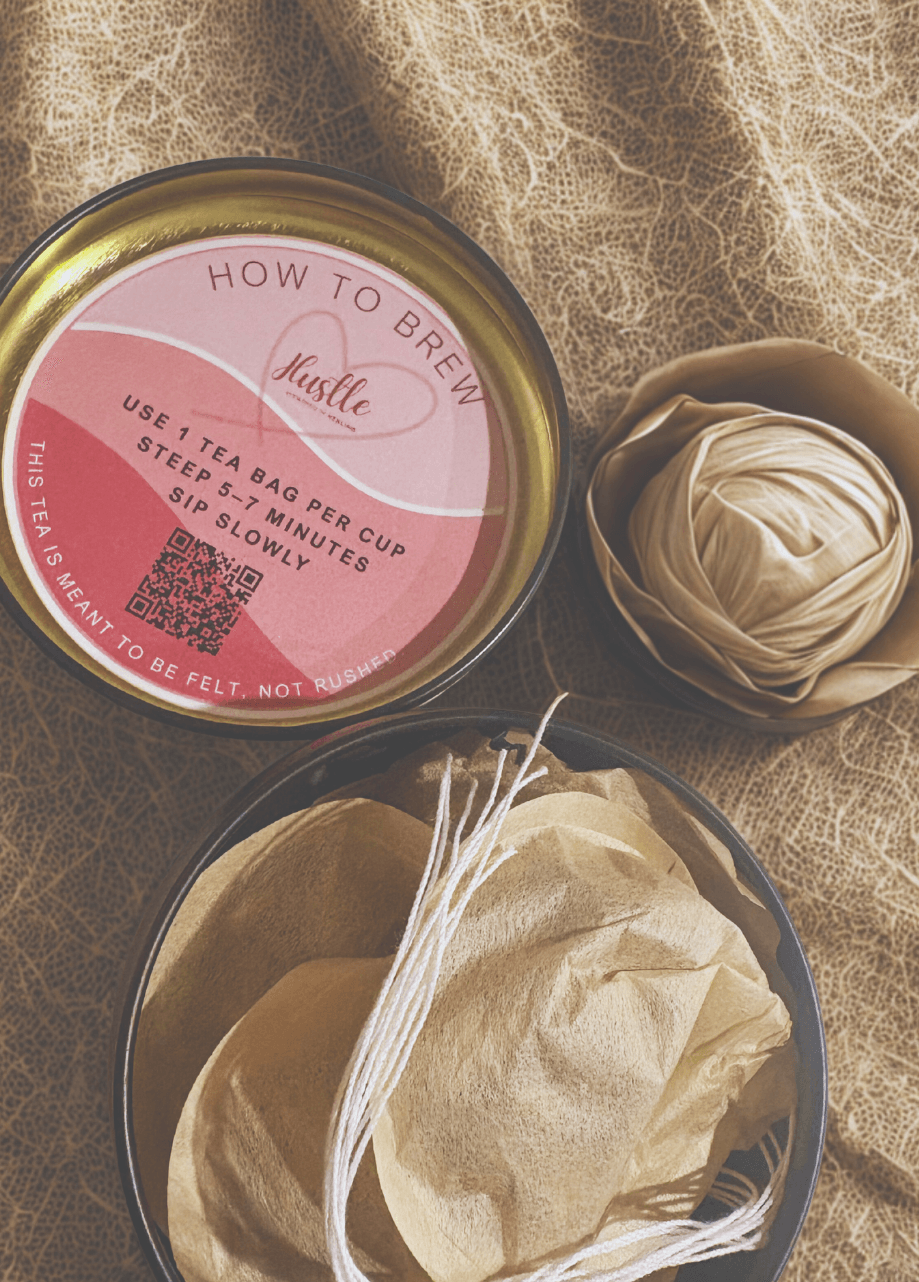 Tea brewing kit with a pink label, a tea bag, and a ball of string on textured fabric.