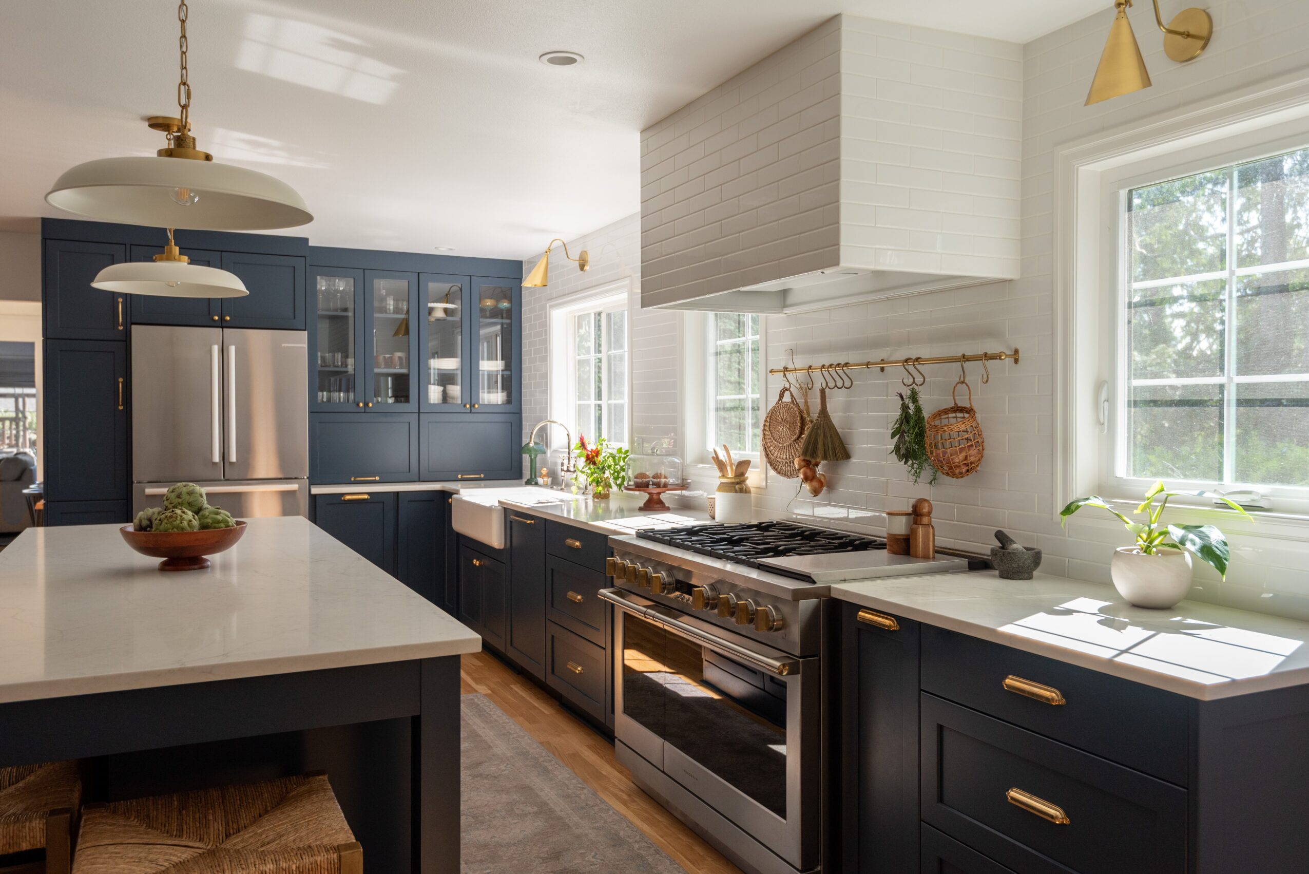 Modern kitchen with dark cabinets, white countertops, stainless steel appliances, and large windows letting in natural light.