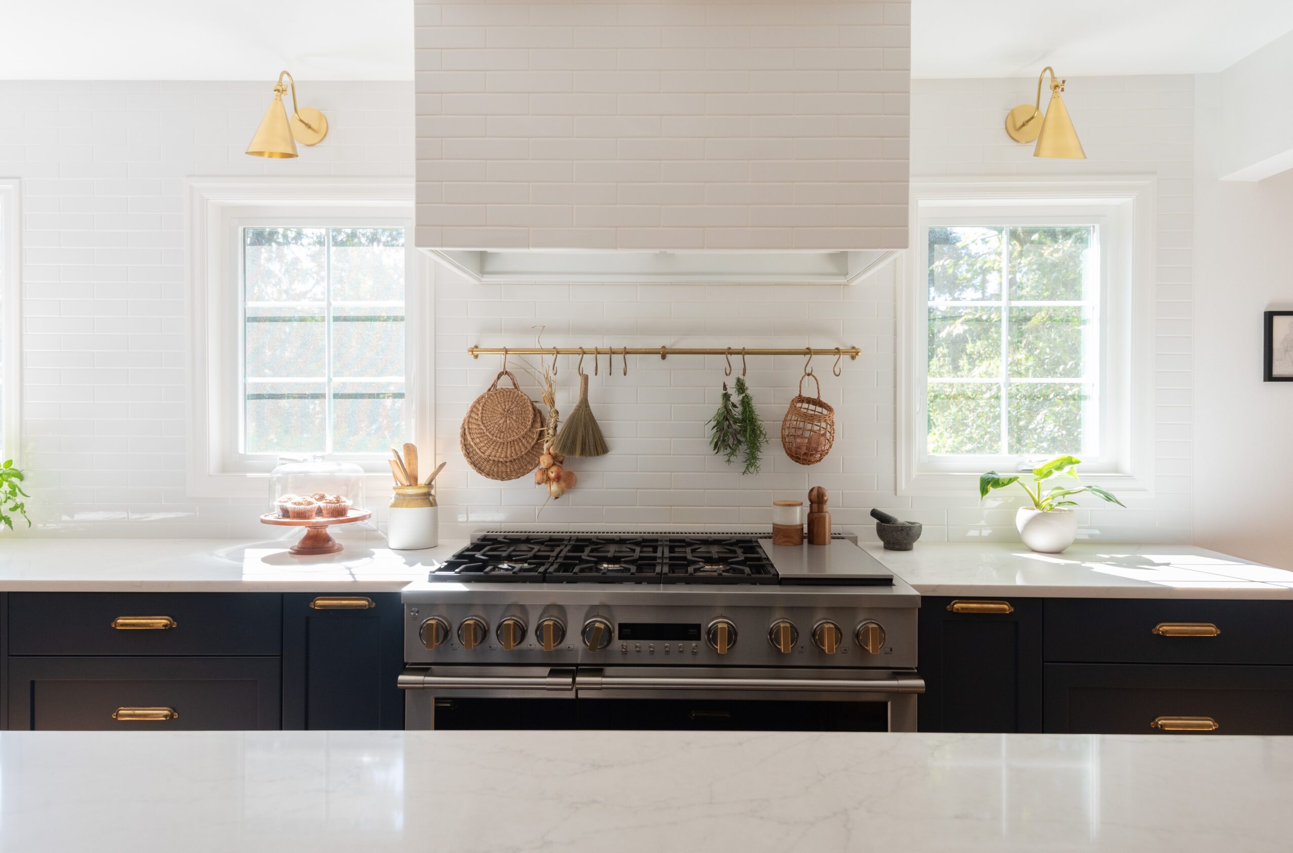 Kitchen with stove, two windows, hanging baskets, and countertop decor, bright and modern design.