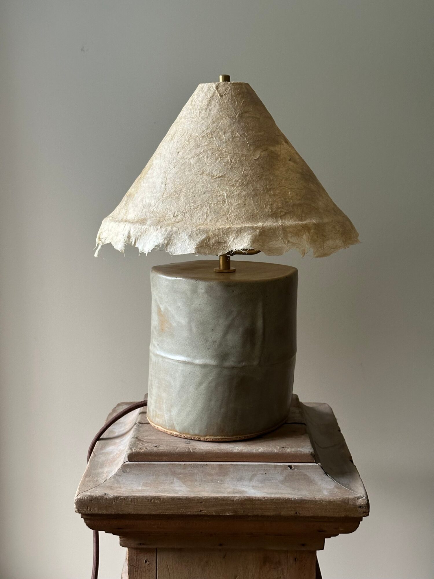 Upright lamp with a conical shade on a wooden base, against a plain background.