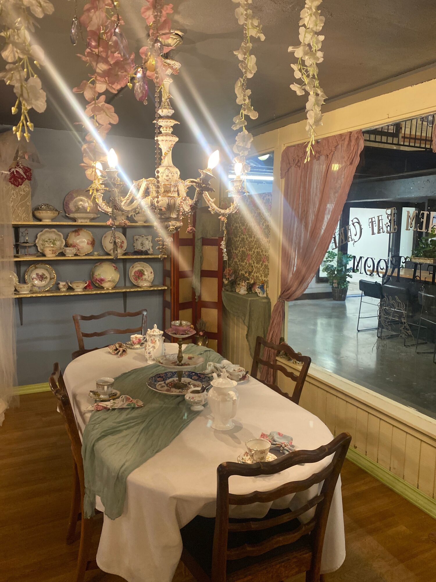 Dining room with a table set with a white tablecloth, floral centerpiece, and chairs, viewed from the side.