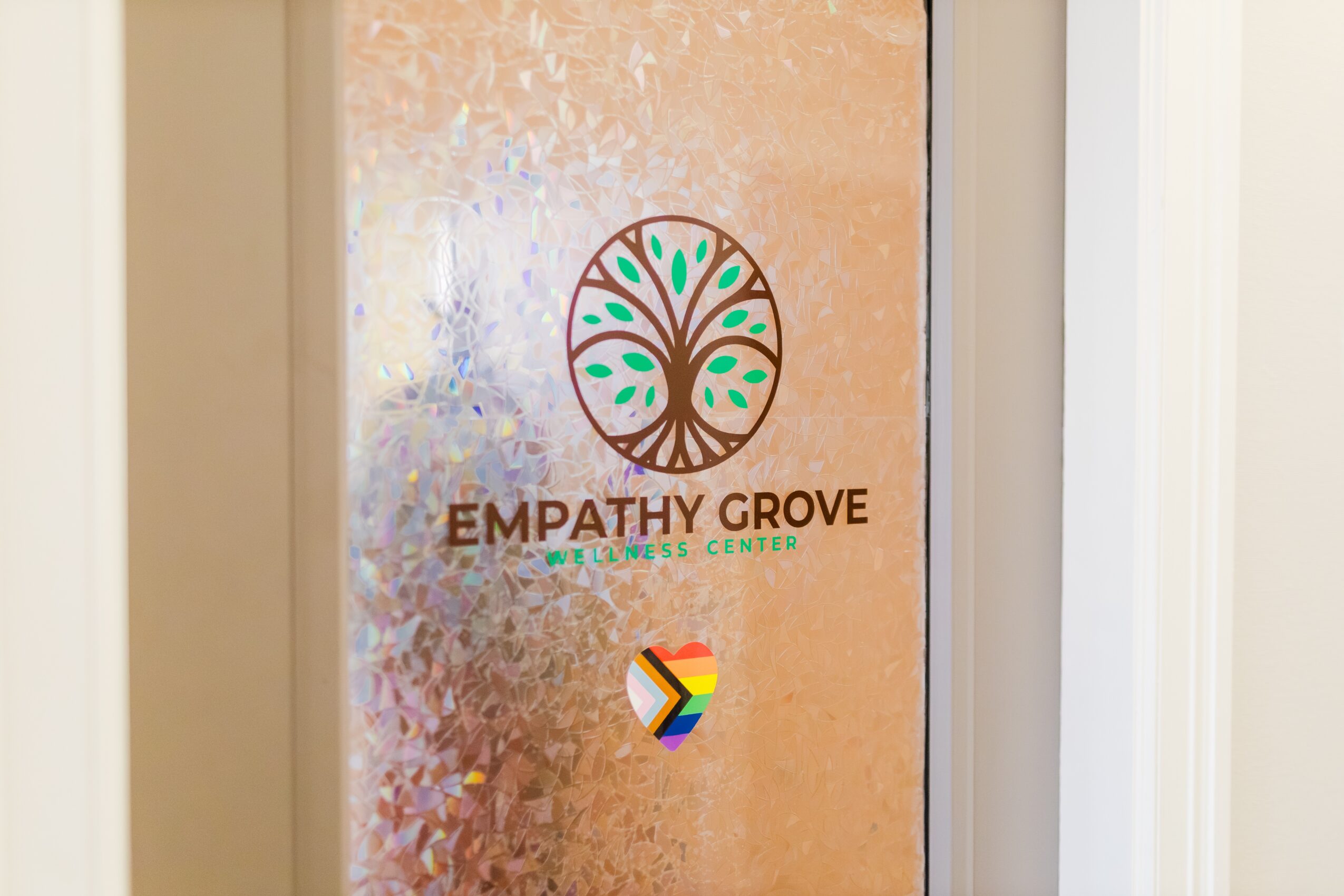 Frosted glass door with a colorful tree logo and the words 'Empathy Grove' and 'Center' below it.