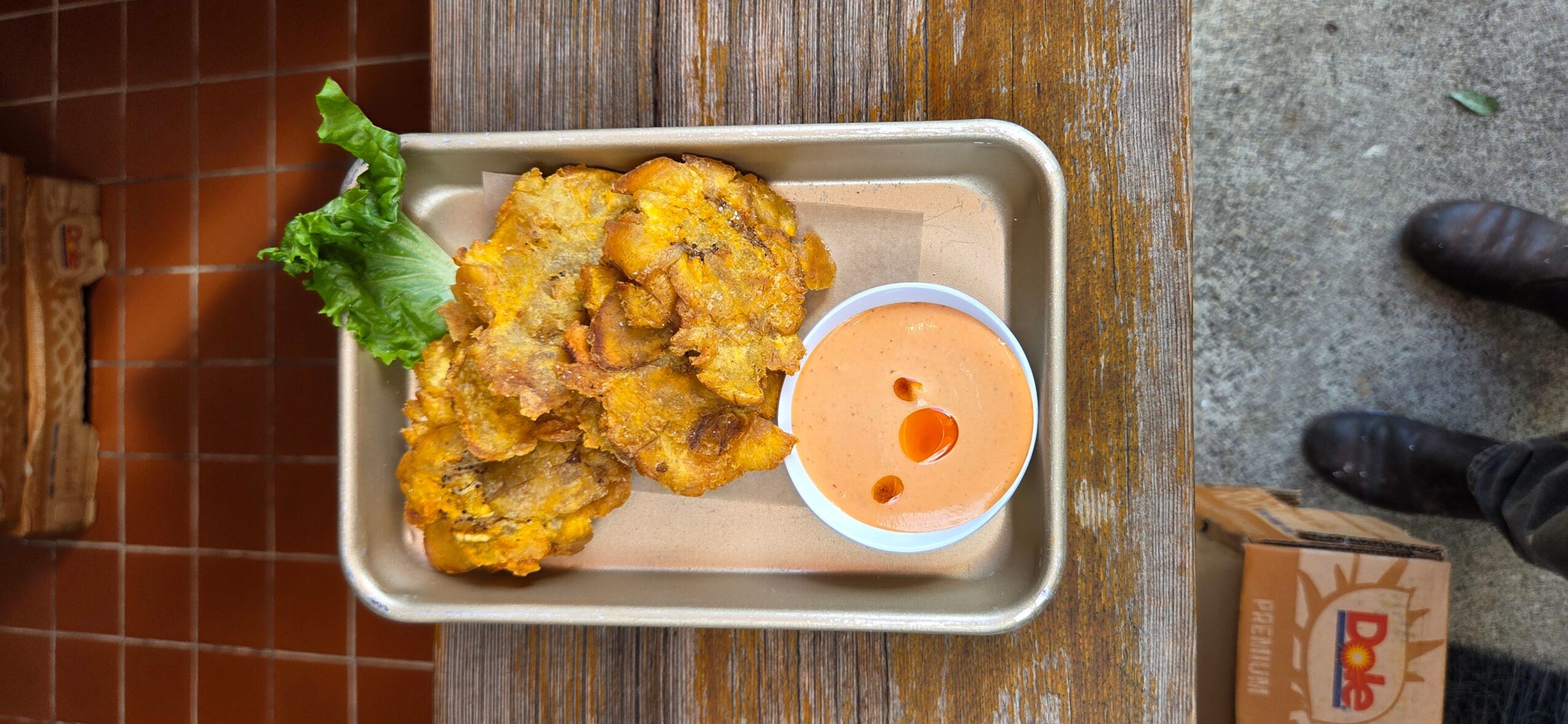 Fried chicken with lettuce and dipping sauce on a tray, viewed from above, on a wooden table.