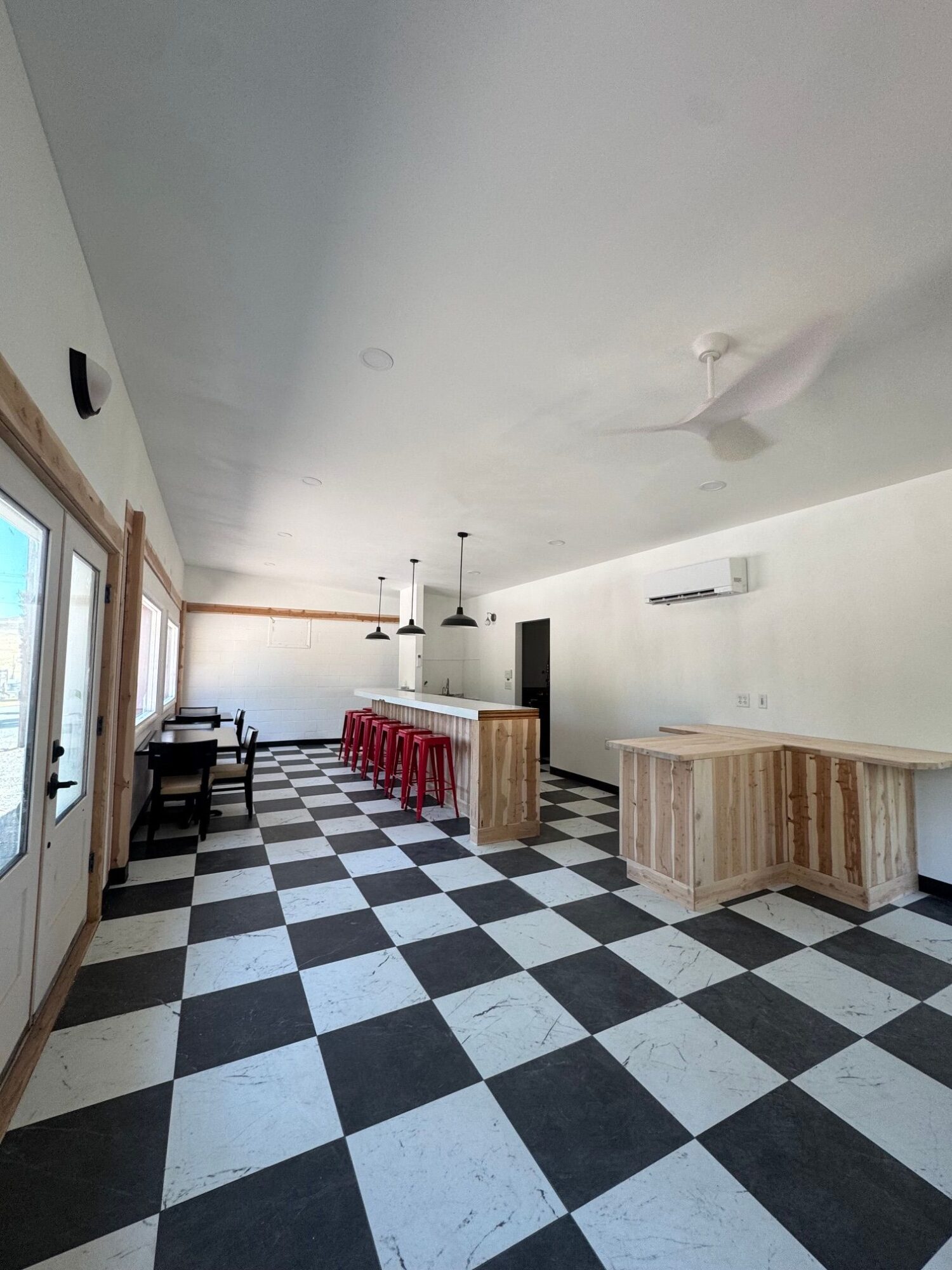 Room with checkered black and white floor, wooden furniture, and a window with curtains.