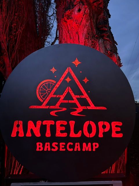 Round sign with red text and graphics reading 'Antelope Basecamp' and a stylized mountain and wheel design.