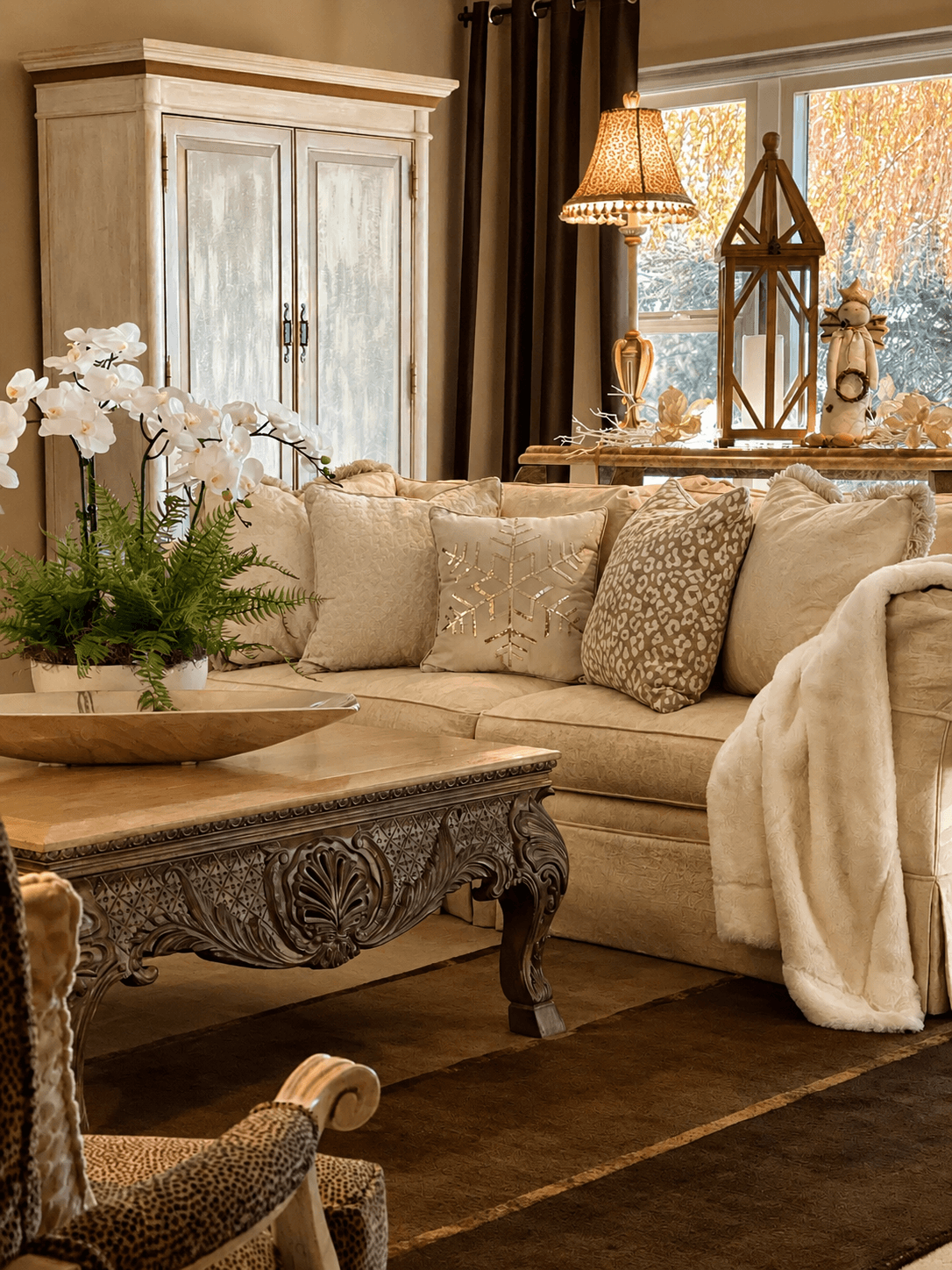 Living room with beige sofa, decorative pillows, wooden coffee table, and window with curtains, autumn scenery outside, warm lighting.