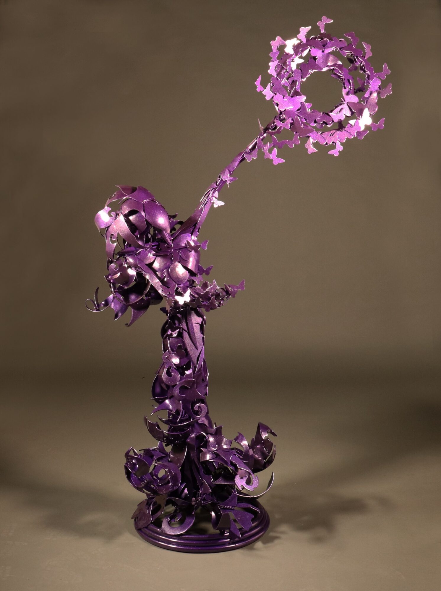 Purple abstract sculpture with a circular element at the top, set against a plain background.