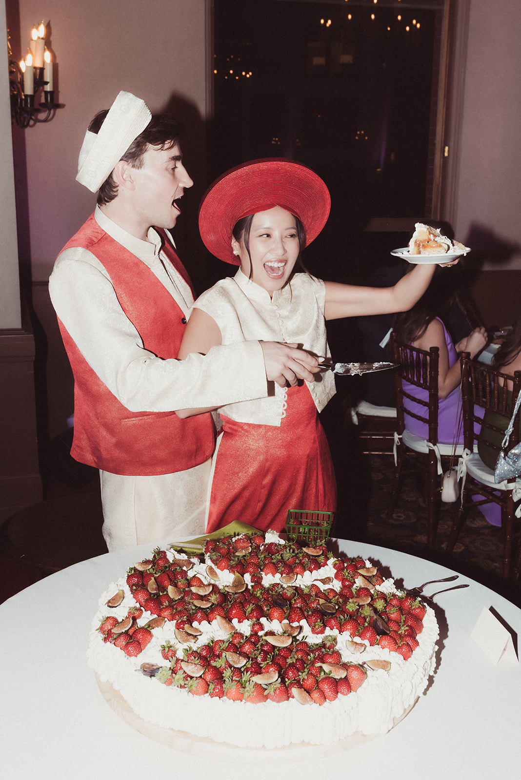 Two children, a boy and a girl, celebrate with a cake at a party, girl holding a plate with a slice of cake.