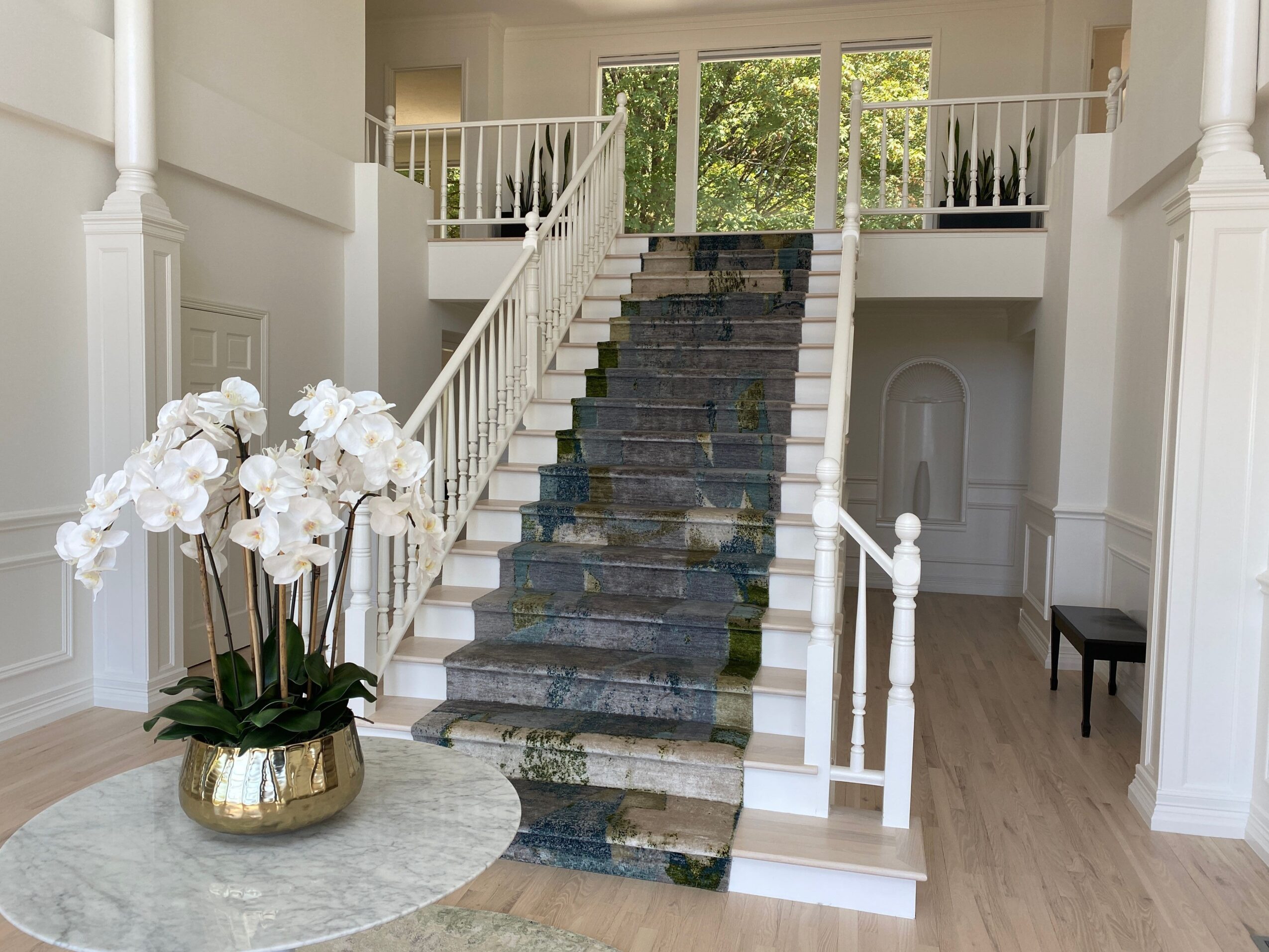 View of a staircase with a stone pathway, white railings, and a chandelier with white flowers hanging from the ceiling.