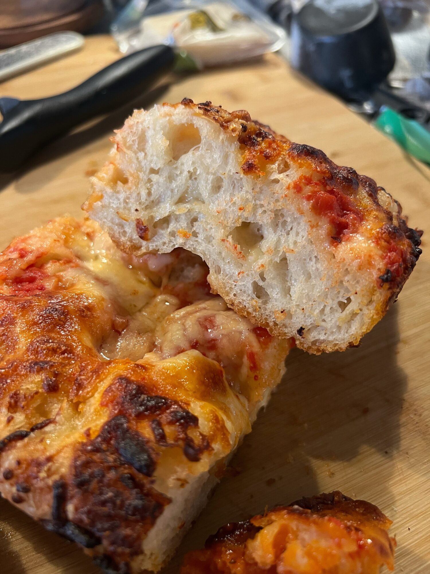 Close-up of a slice of pizza bread with melted cheese and tomato sauce, showing a soft interior and crispy crust.