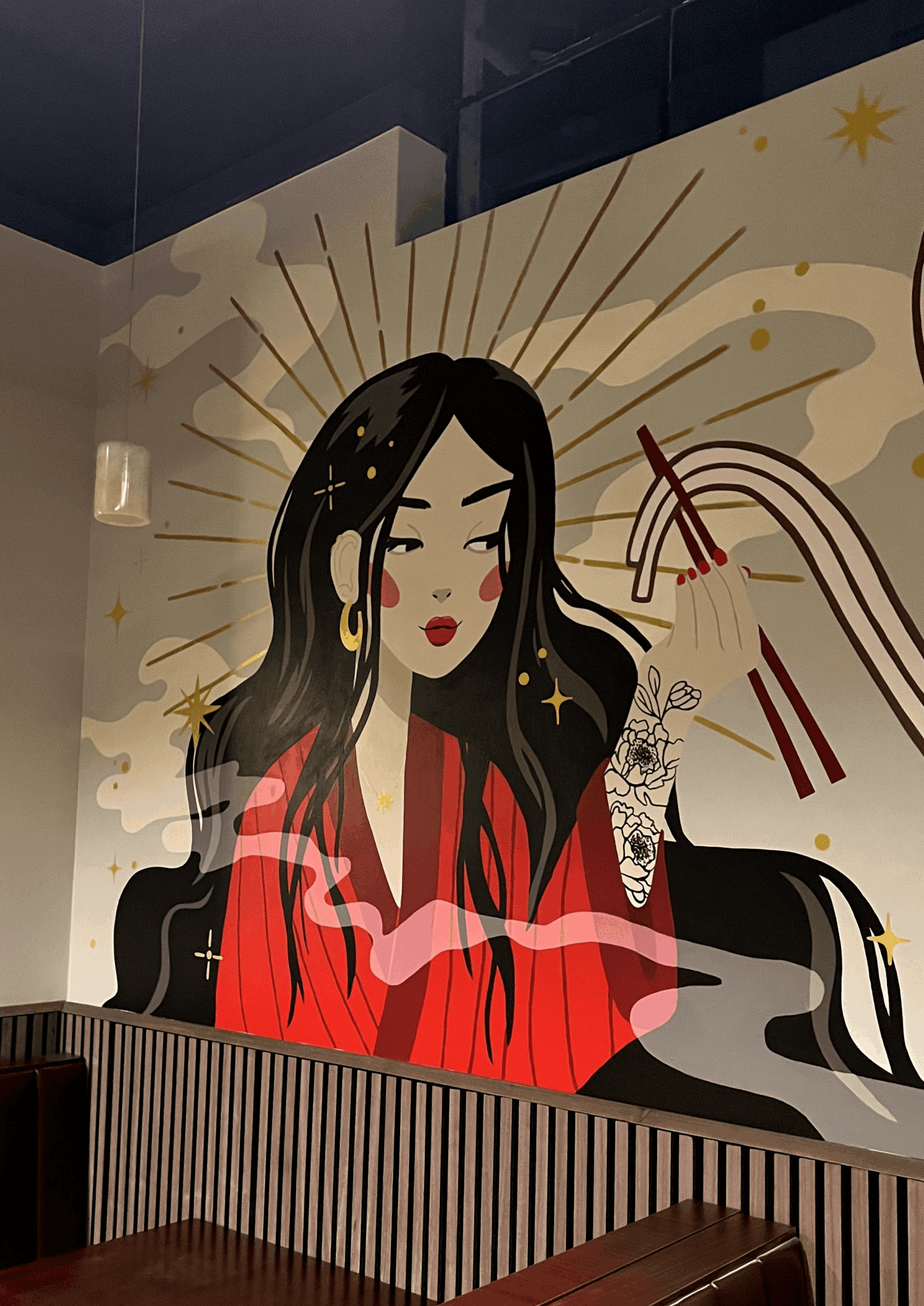 Illustration of a woman with long black hair, red dress, and gold earrings, surrounded by golden rays and stars.