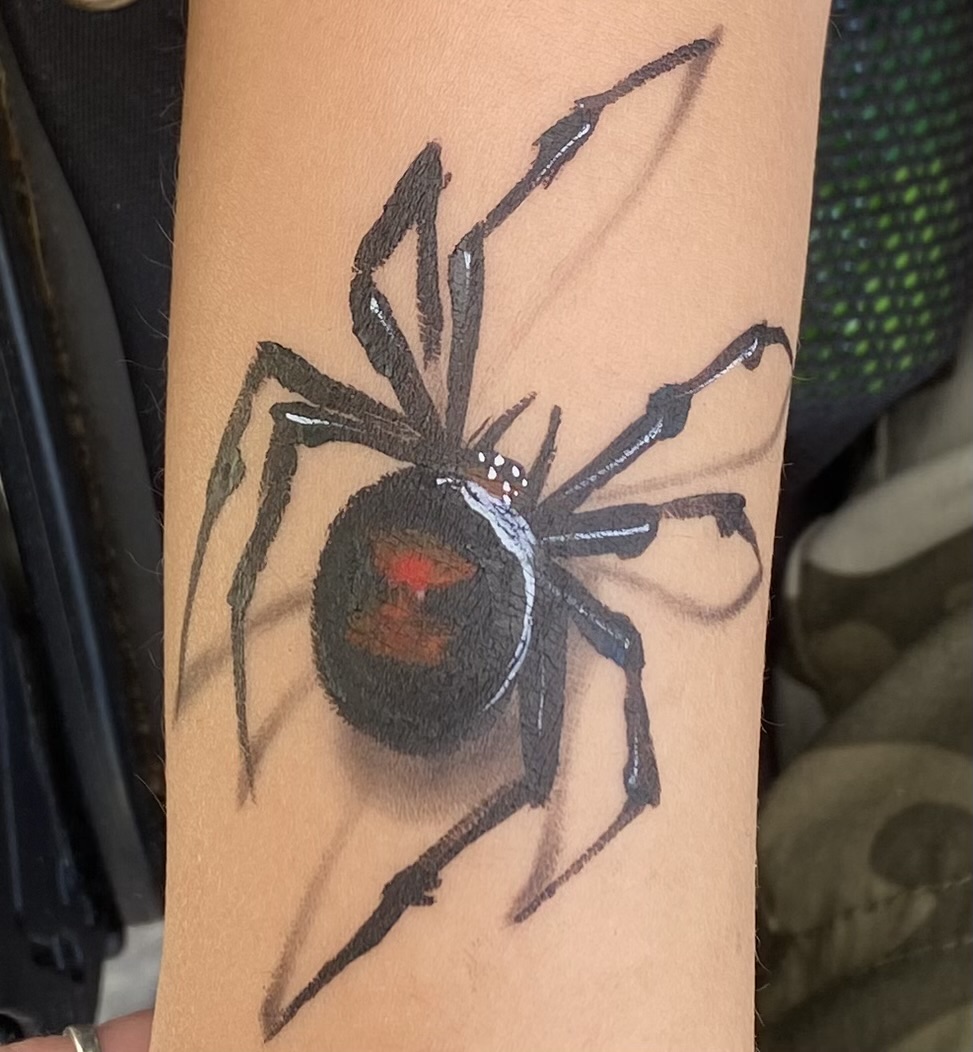 Tattoo of a black and red spider on skin, with detailed legs and body.