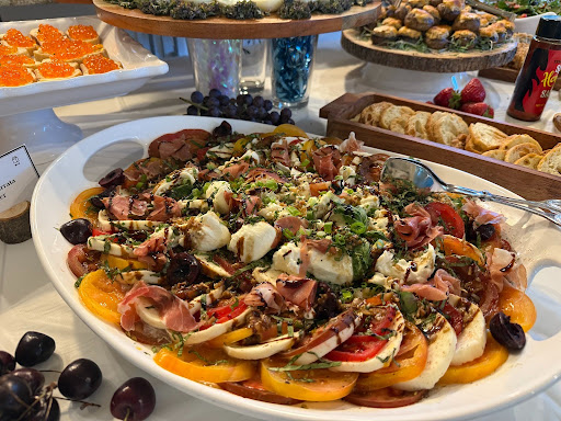 Large platter of assorted sliced vegetables, cheeses, meats, and olives, garnished with herbs, on a white serving dish.