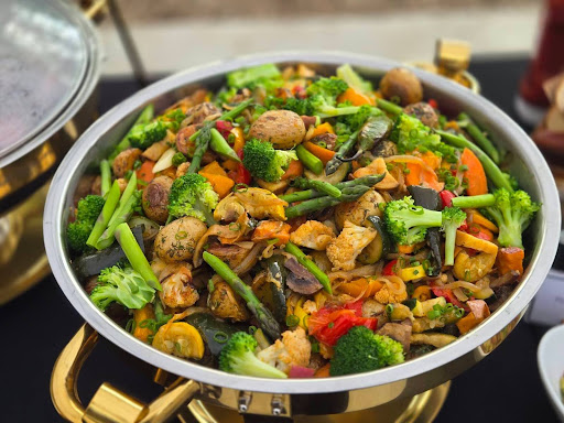Mixed stir-fry with broccoli, carrots, mushrooms, and other vegetables in a large pan.