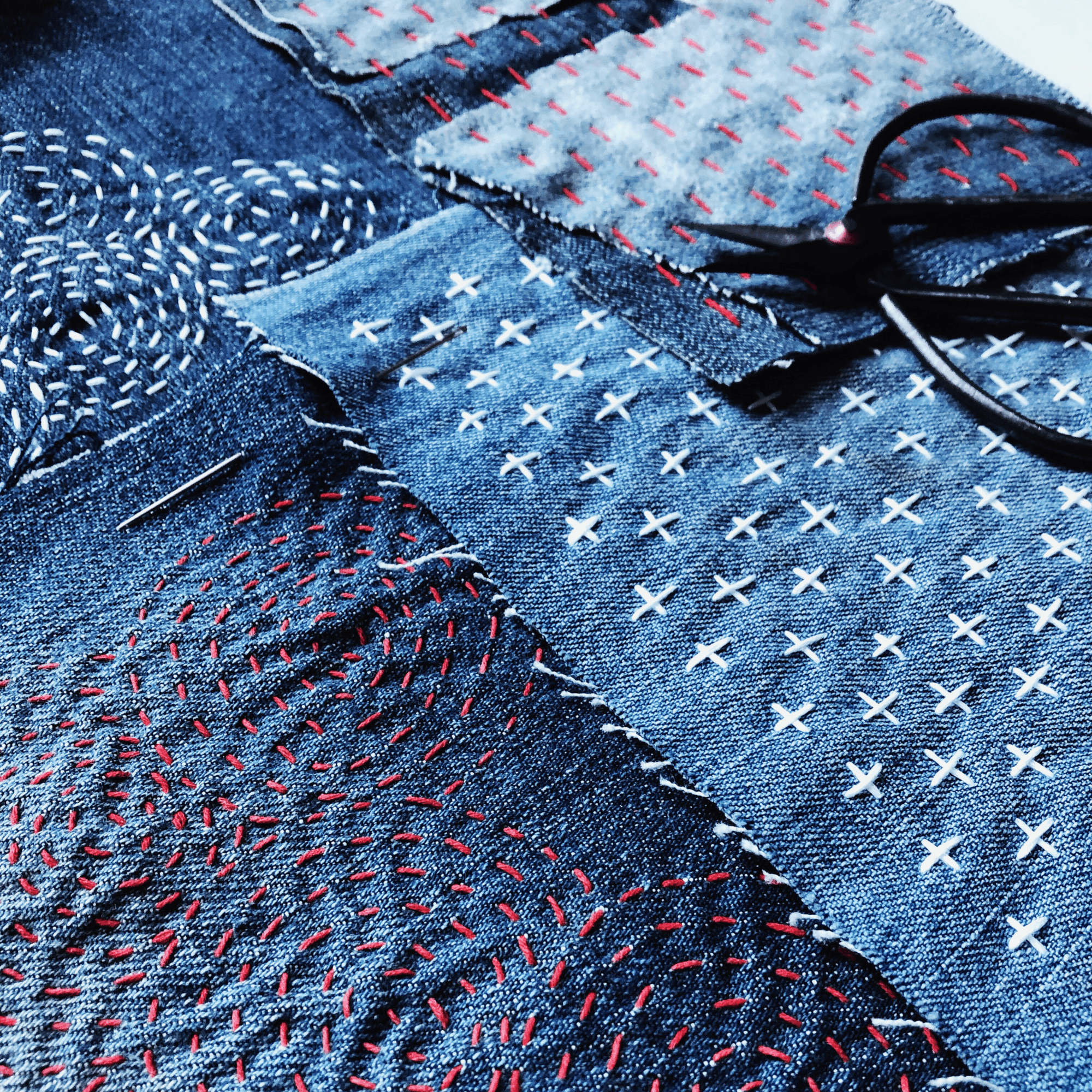 Close-up of various denim fabric patches with colorful stitching and embroidery details.