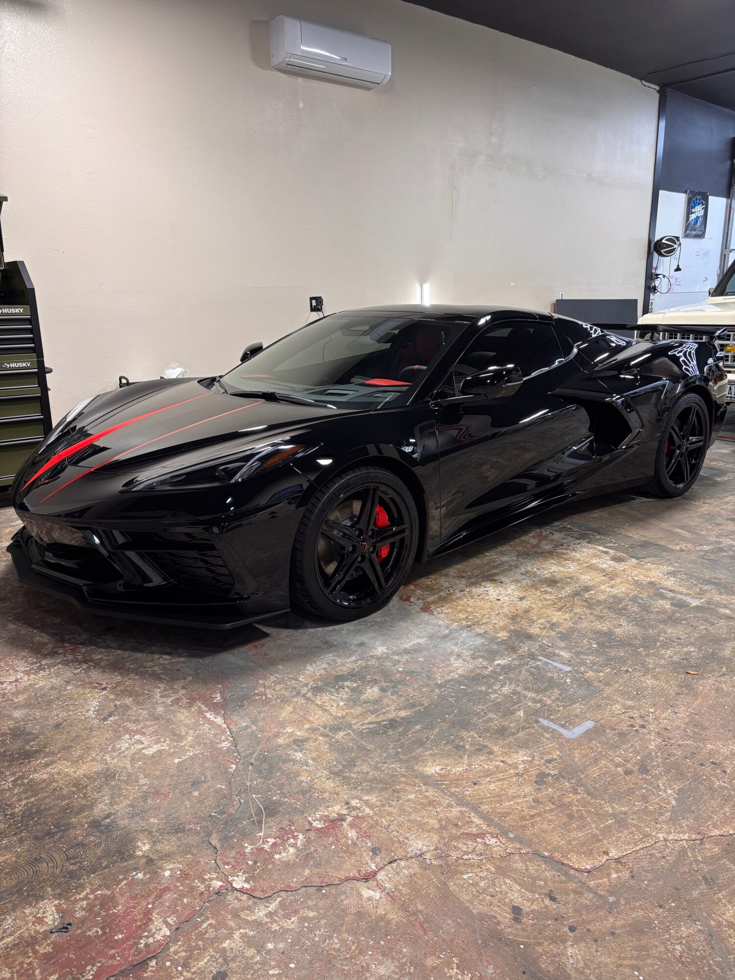 Black sports car with red accents parked indoors on a concrete floor.