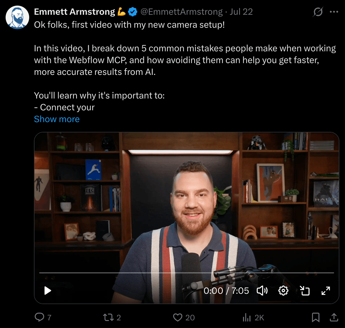 Man with beard and striped shirt smiling in front of bookshelf, speaking into microphone, in a video thumbnail.