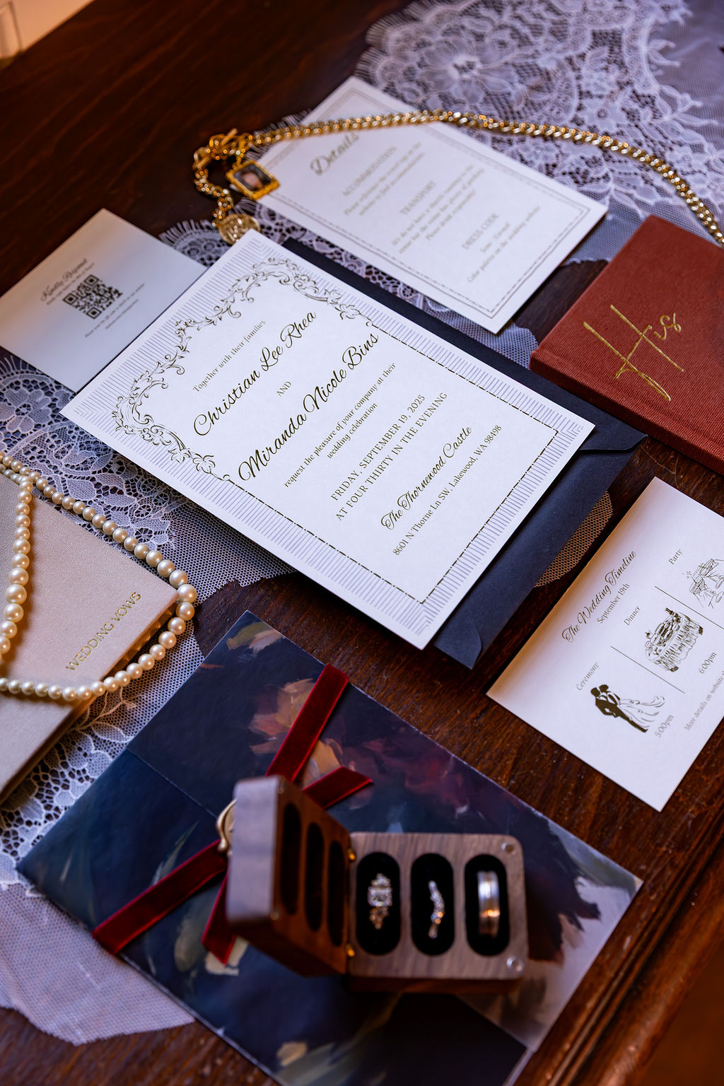 Wedding invitation, pearl necklace, and other items on a lace tablecloth, with a wooden surface nearby.