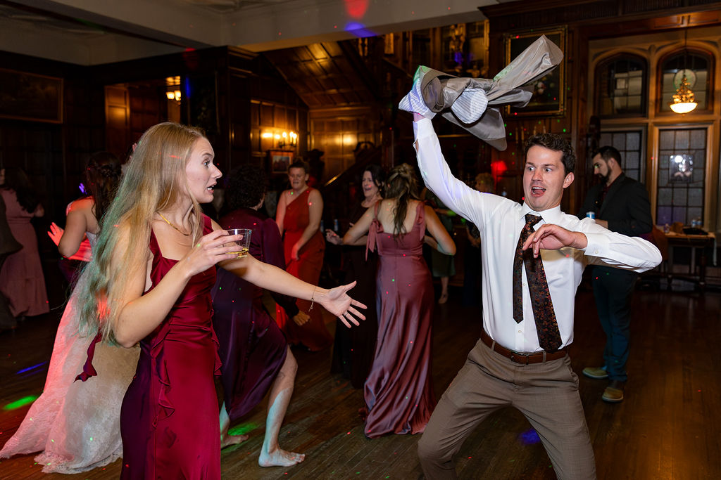 People dancing and celebrating in a decorated indoor venue with wooden walls and warm lighting.