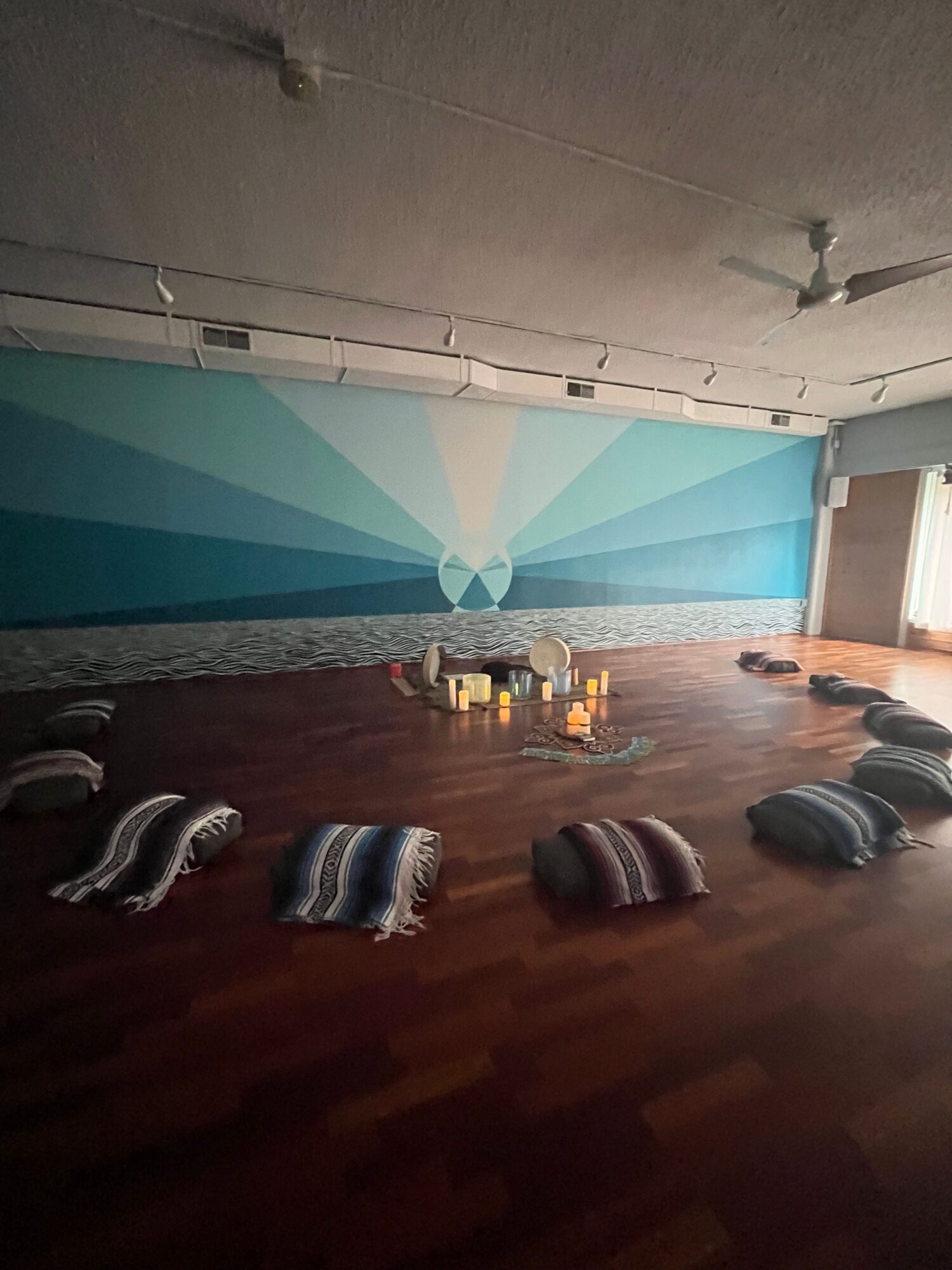 Room with a large wall mural, wooden floor, and various shoes on the floor, viewed from the side.