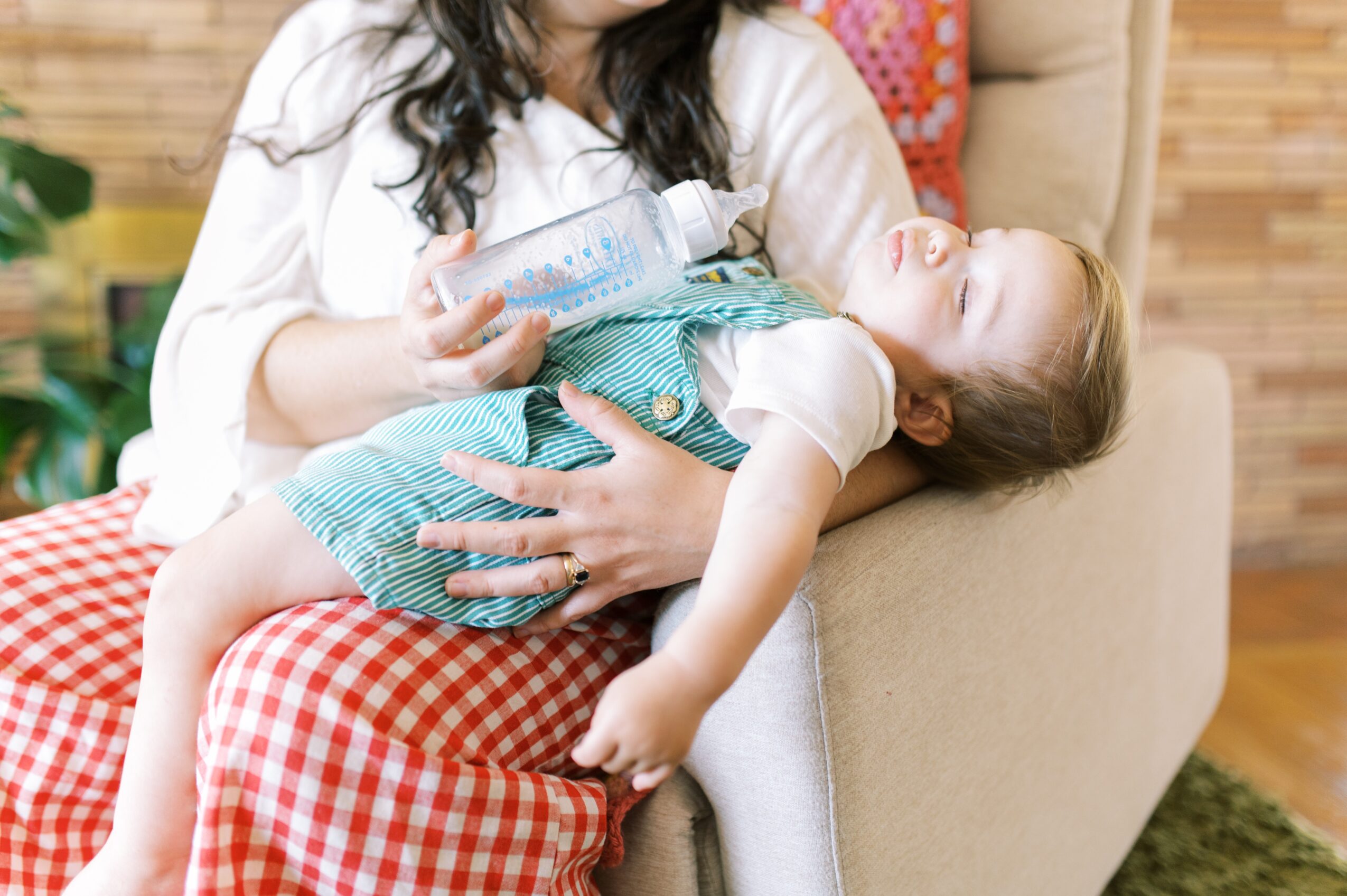 Child lying on adult's lap, smiling with eyes closed, in a cozy indoor setting.