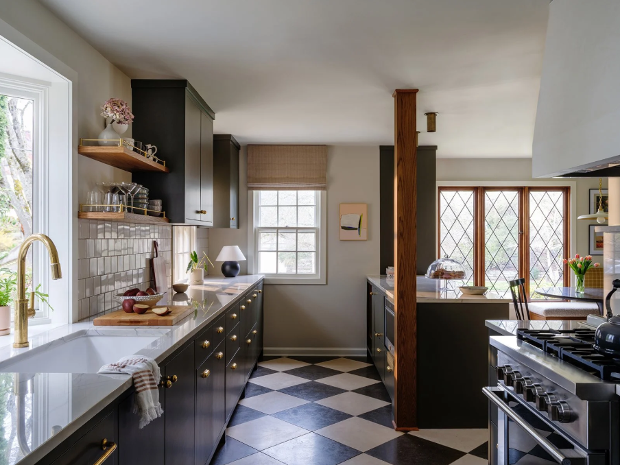 Kitchen with black cabinets, white countertops, checkered floor, window, and a dining area with large glass doors.