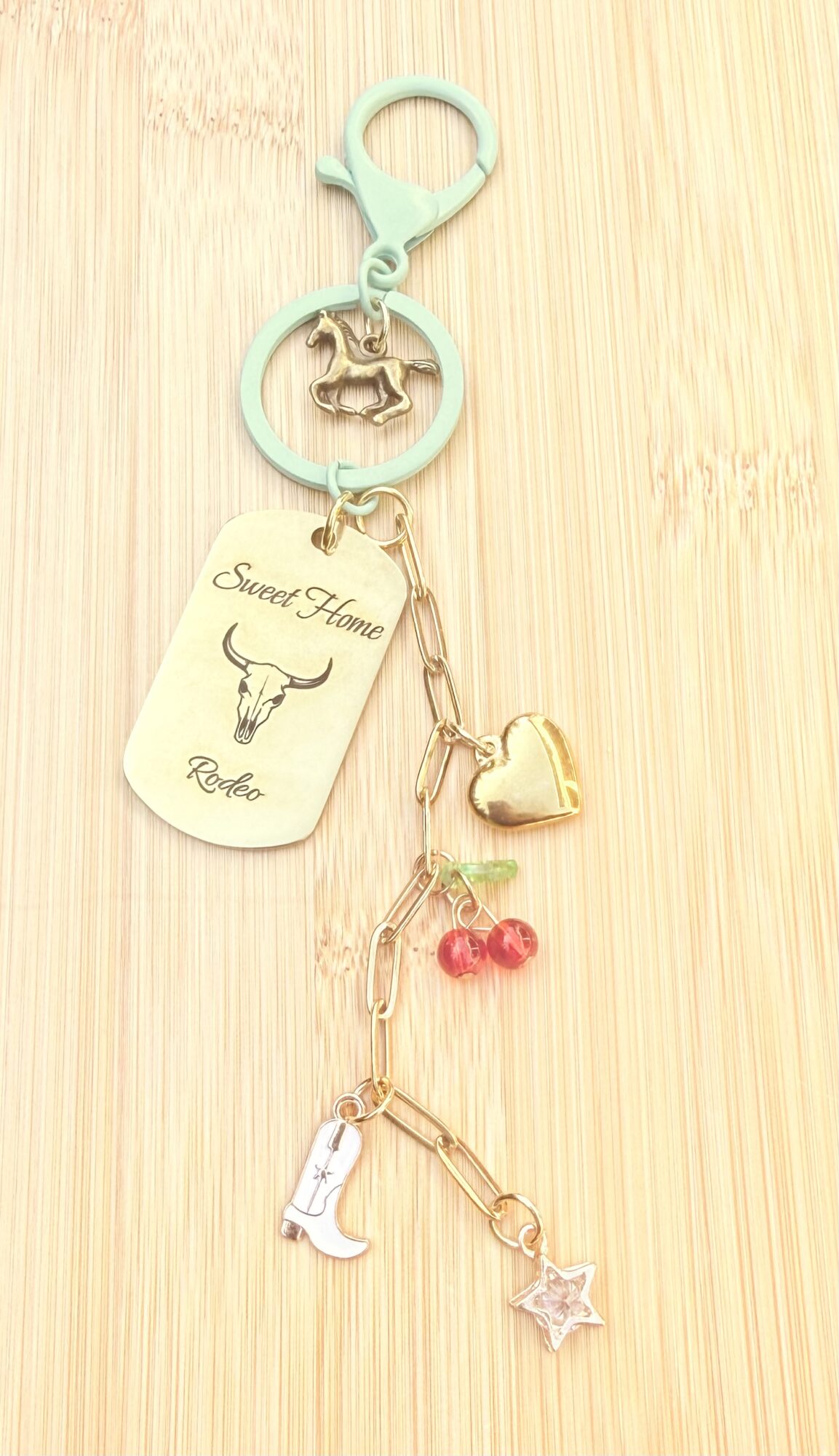 Keychain with a horse charm, dog tag, heart, boot, and star charms on a light wooden surface.