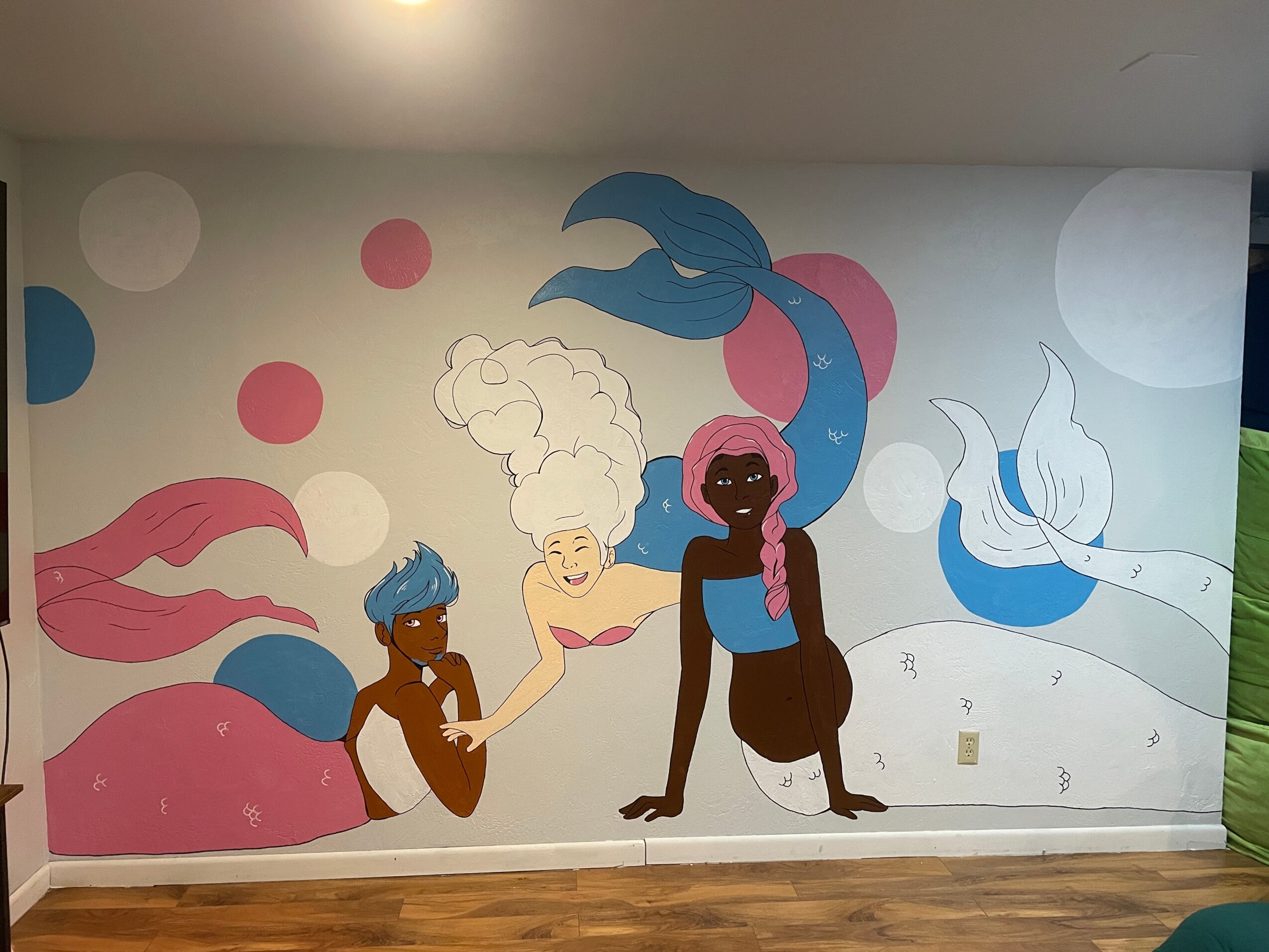 Colorful mural with two mermaids, one with blue hair and the other with pink hair, surrounded by bubbles and abstract shapes.