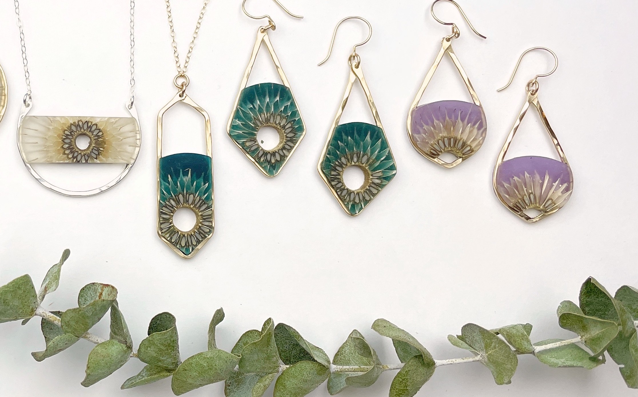 Six pairs of earrings with various colors and designs, displayed on a white background with green leaves at the bottom.