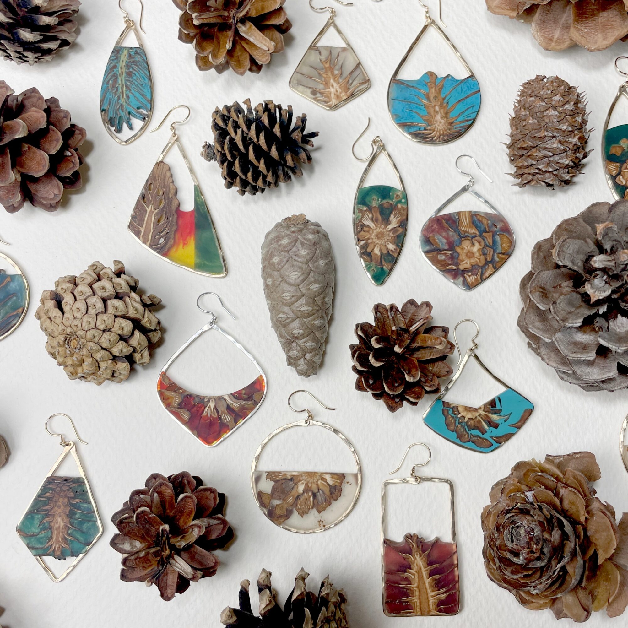 Collection of pinecones and jewelry with pinecone-shaped pendants on a white background.