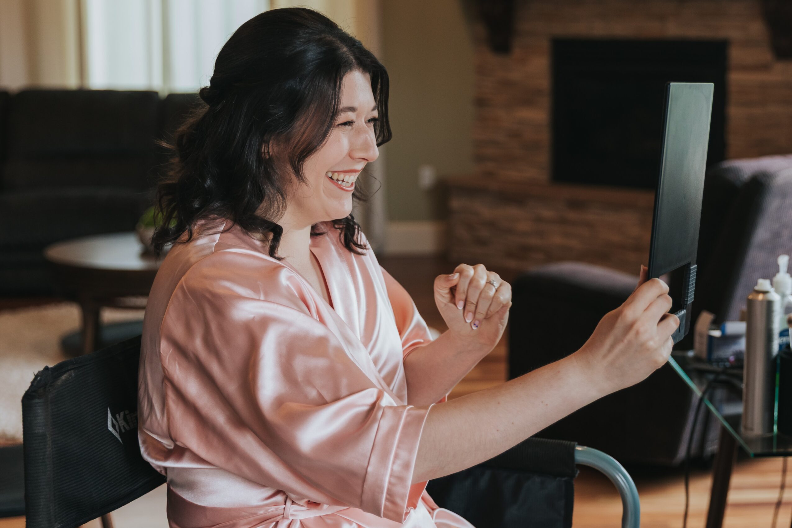 Woman smiling and celebrating while looking at a computer screen in a living room.