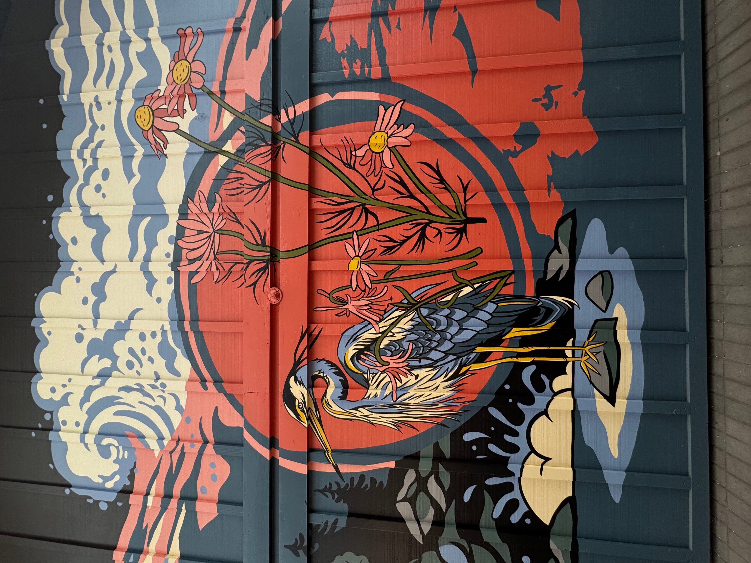 Street art mural featuring a bird, flowers, and abstract shapes on a blue wall.