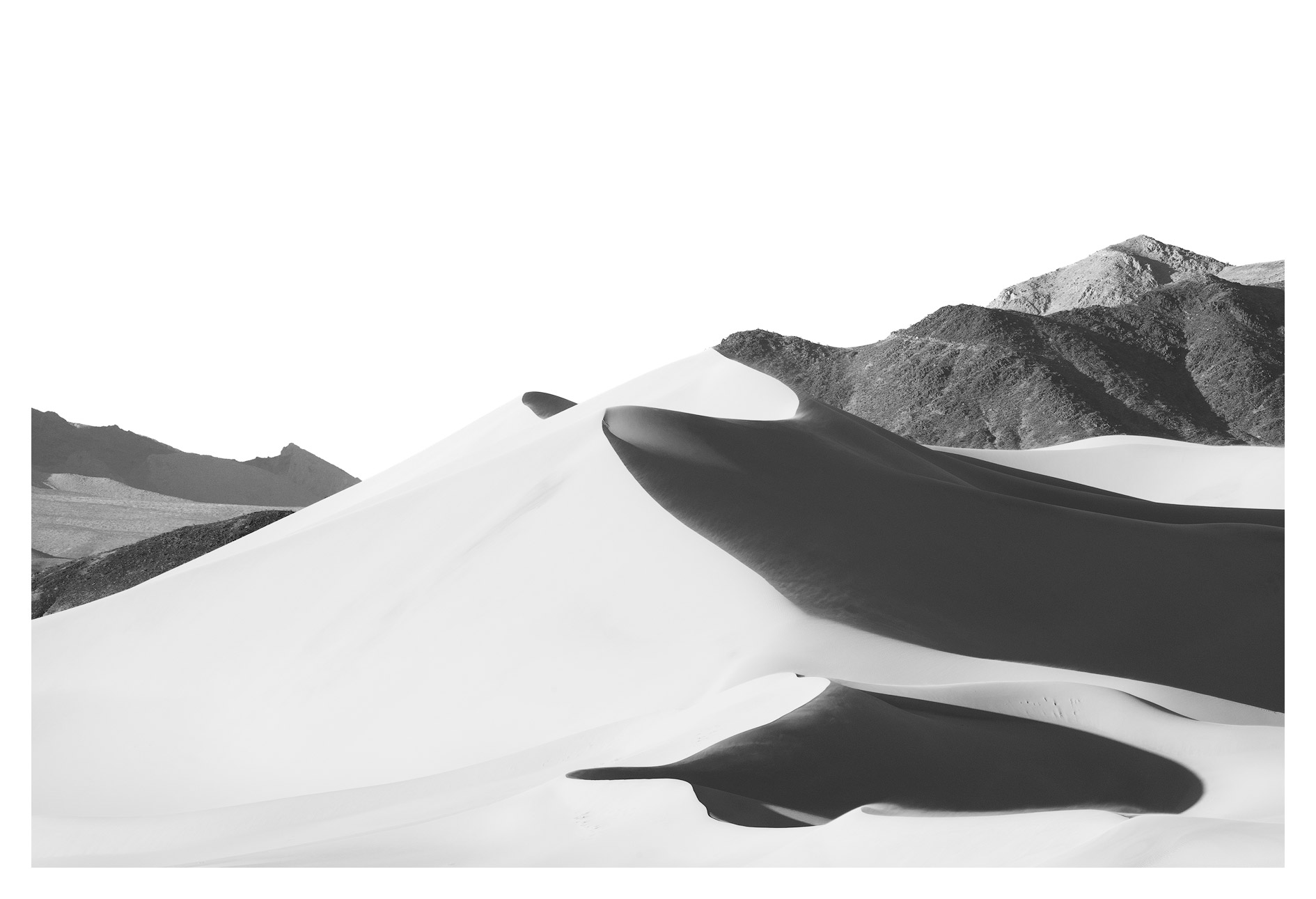 Black and white landscape with sand dunes and mountains in the background.