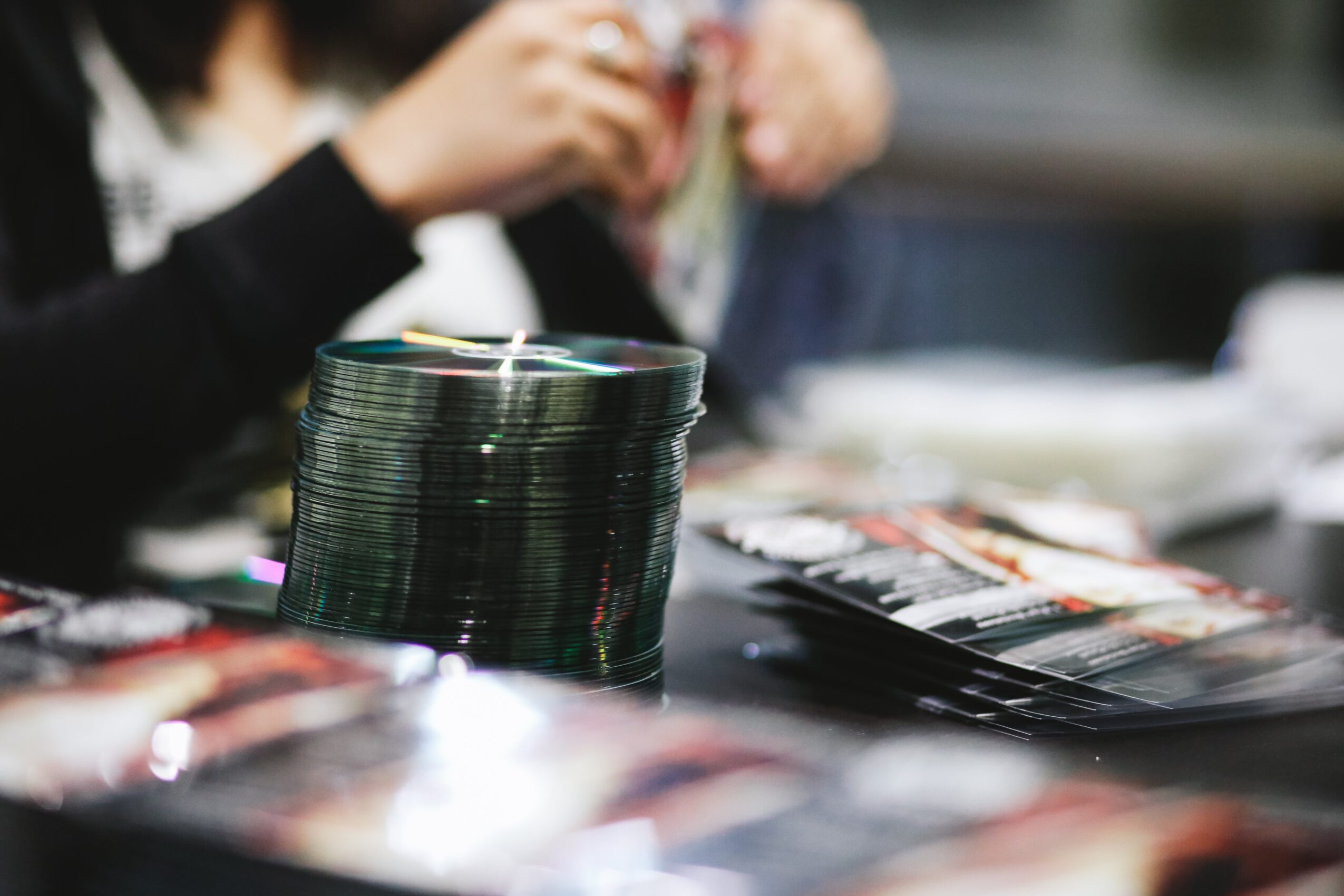Stack of poker chips on a table with people in the background, blurred, in a casino or gaming setting.