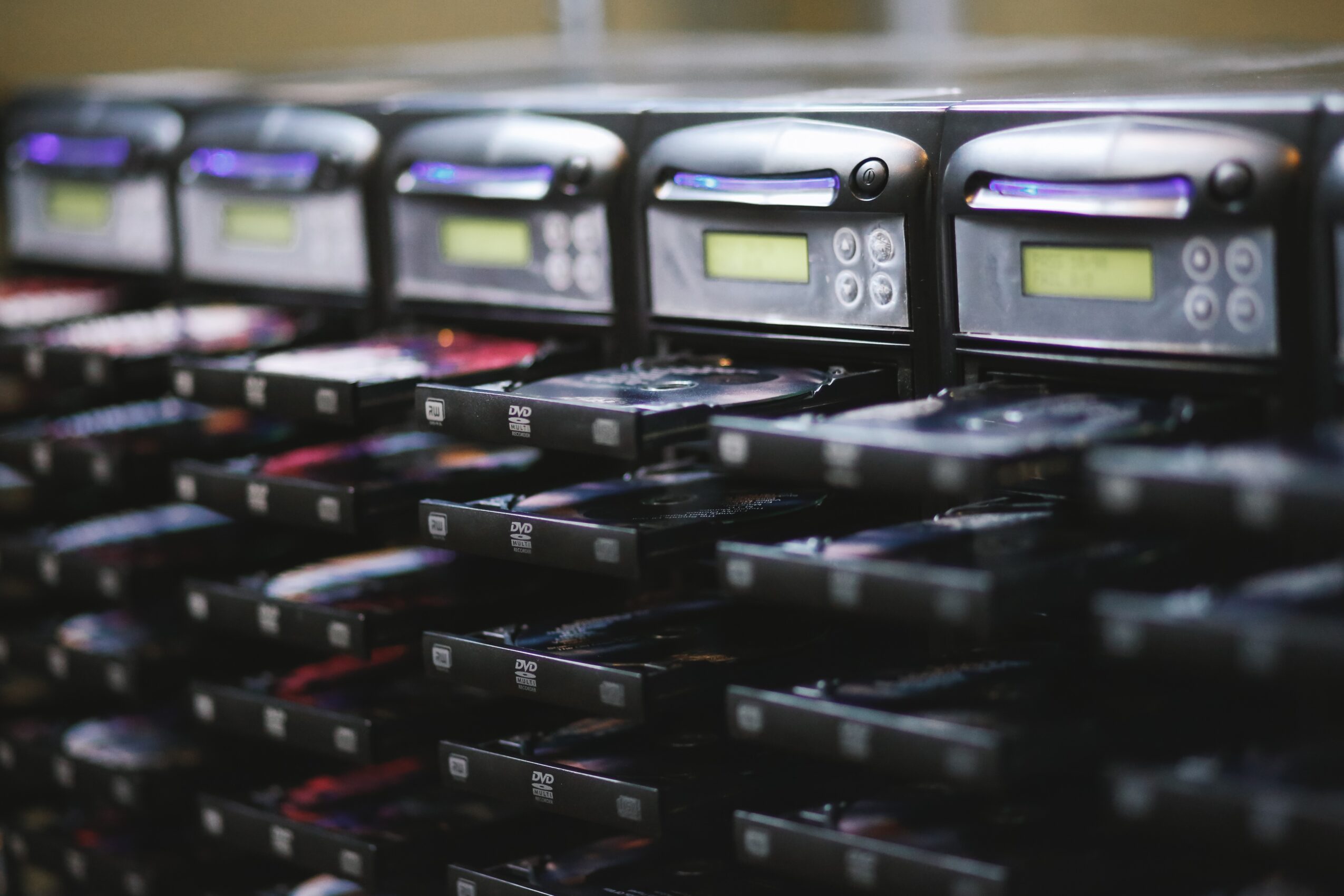 Multiple electronic devices with screens and buttons arranged in rows, possibly in a server room or data center.
