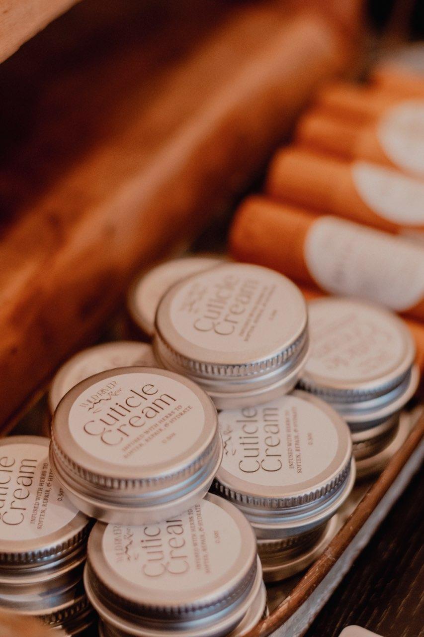 Small jars labeled 'Cullice Cream' arranged on a wooden surface with orange and white objects in the background.