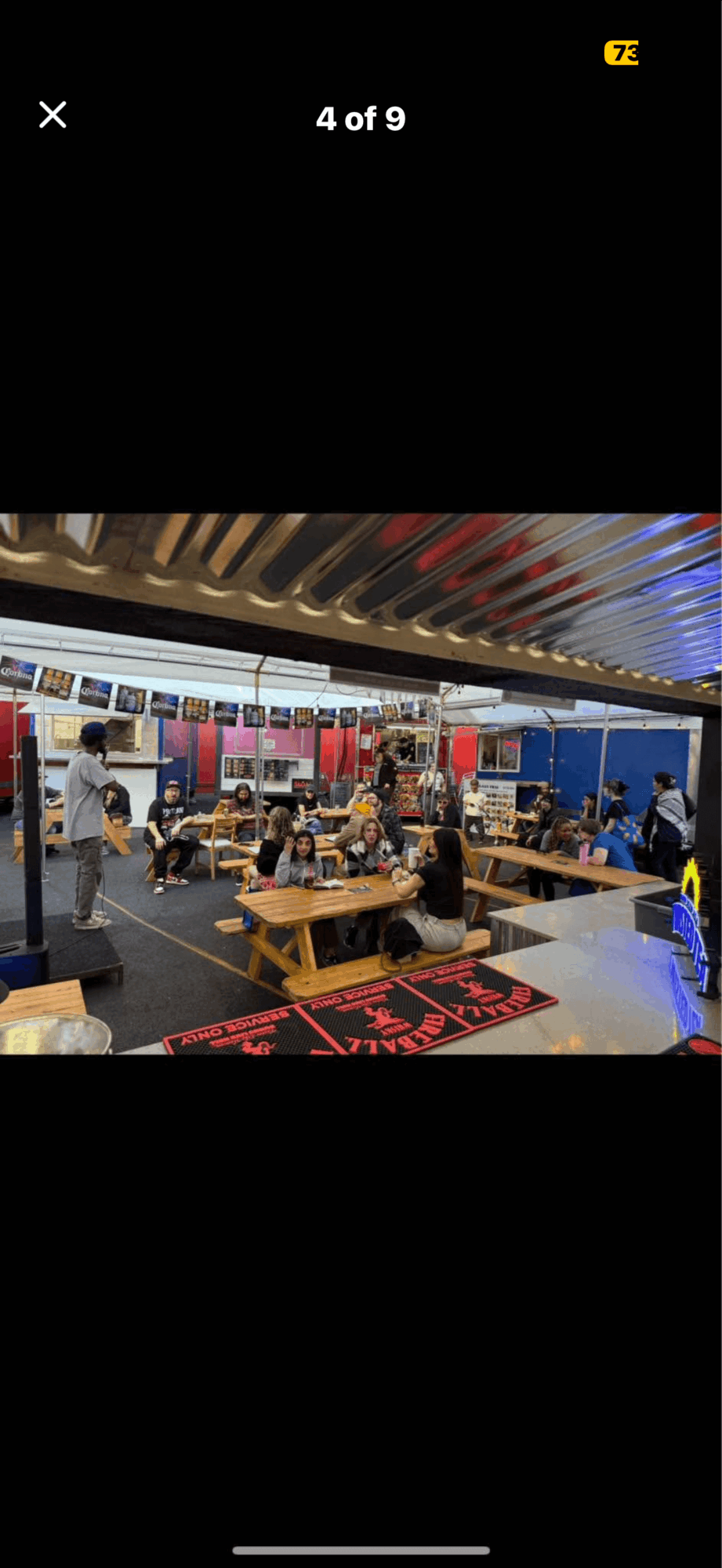 People gather in a retail store with shelves, tables, and colorful displays, some sitting and browsing products.