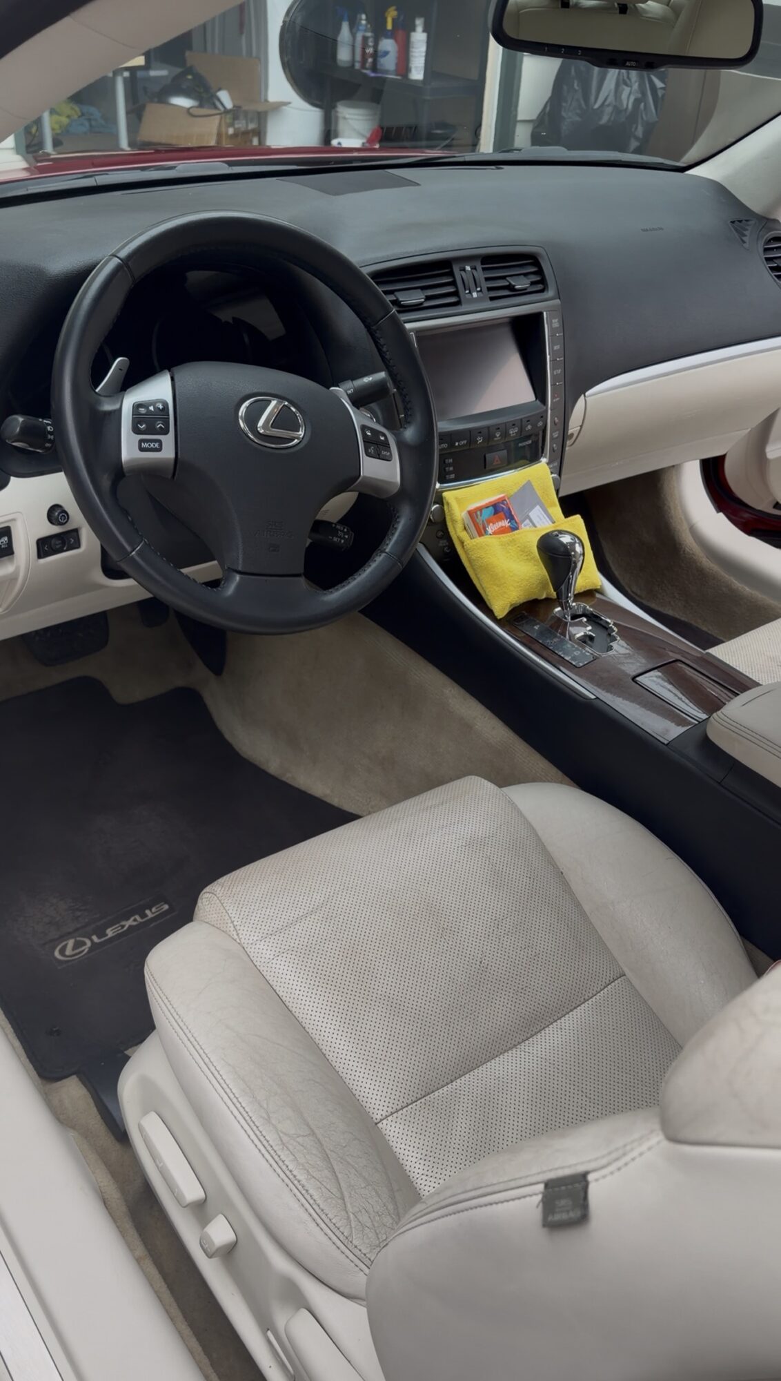 Car interior showing steering wheel, dashboard, center console, and front seat with beige upholstery.